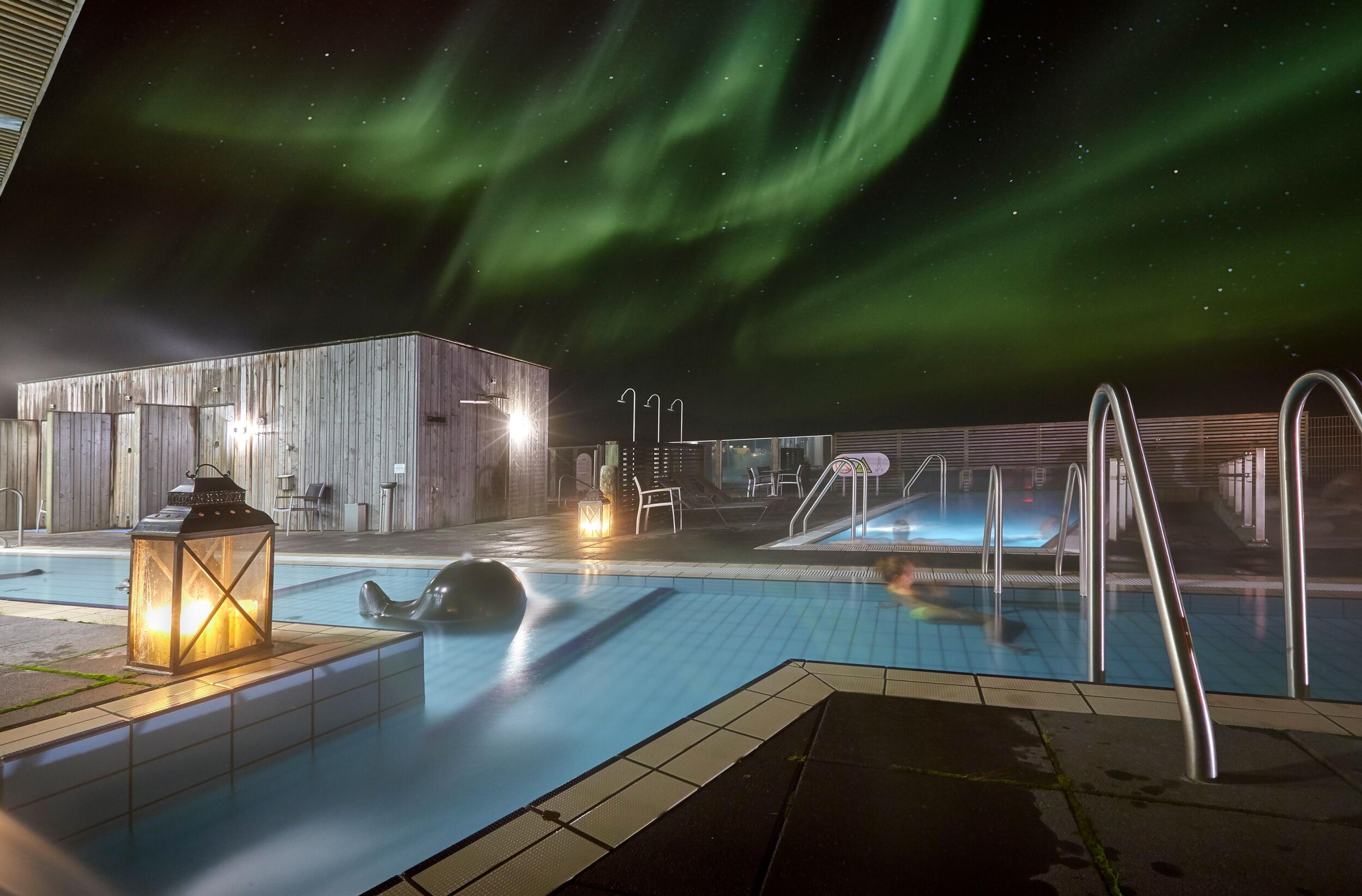  Fontana Bath with geothermal pools under the Northern Lights in the Golden Circle, Iceland. Cozy evening atmosphere with illuminated paths.