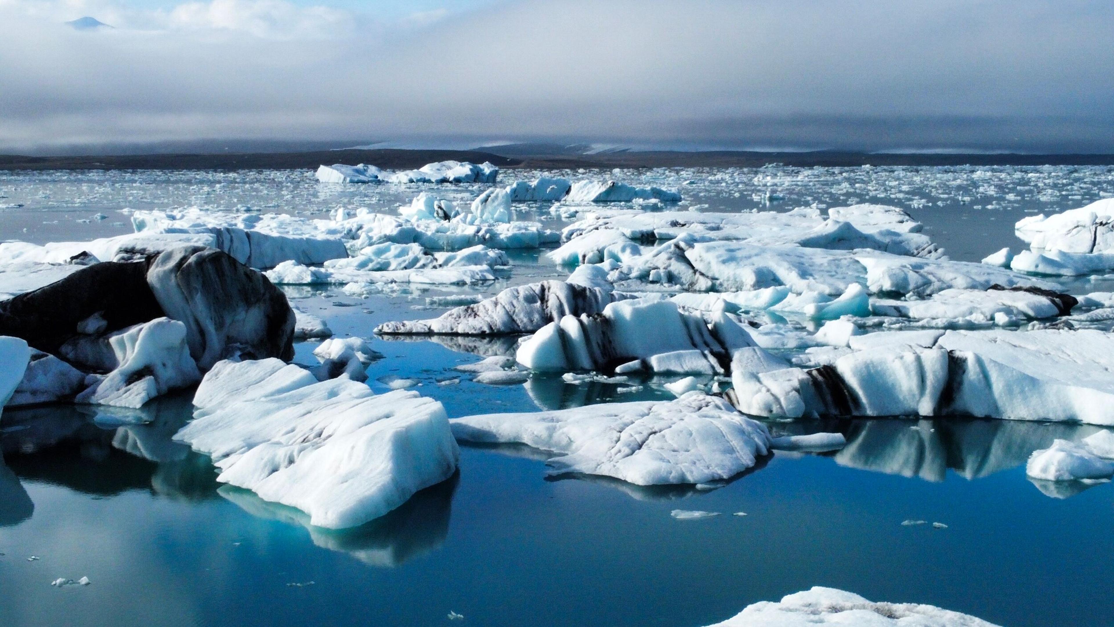 Icebergs floating in a glacial lagoon under an overcast sky.