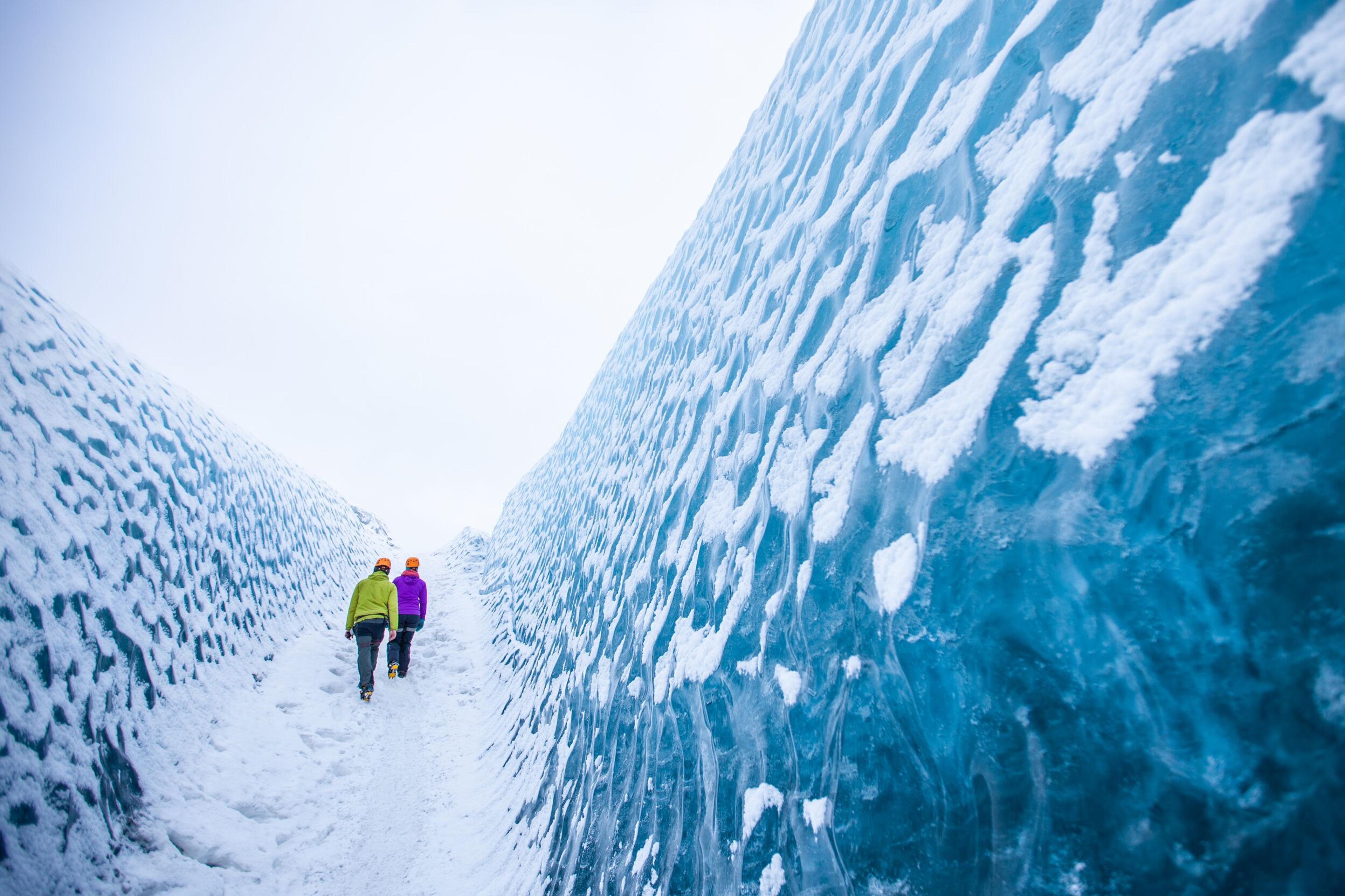 Hikers walking on a blue ice glacier in Iceland.