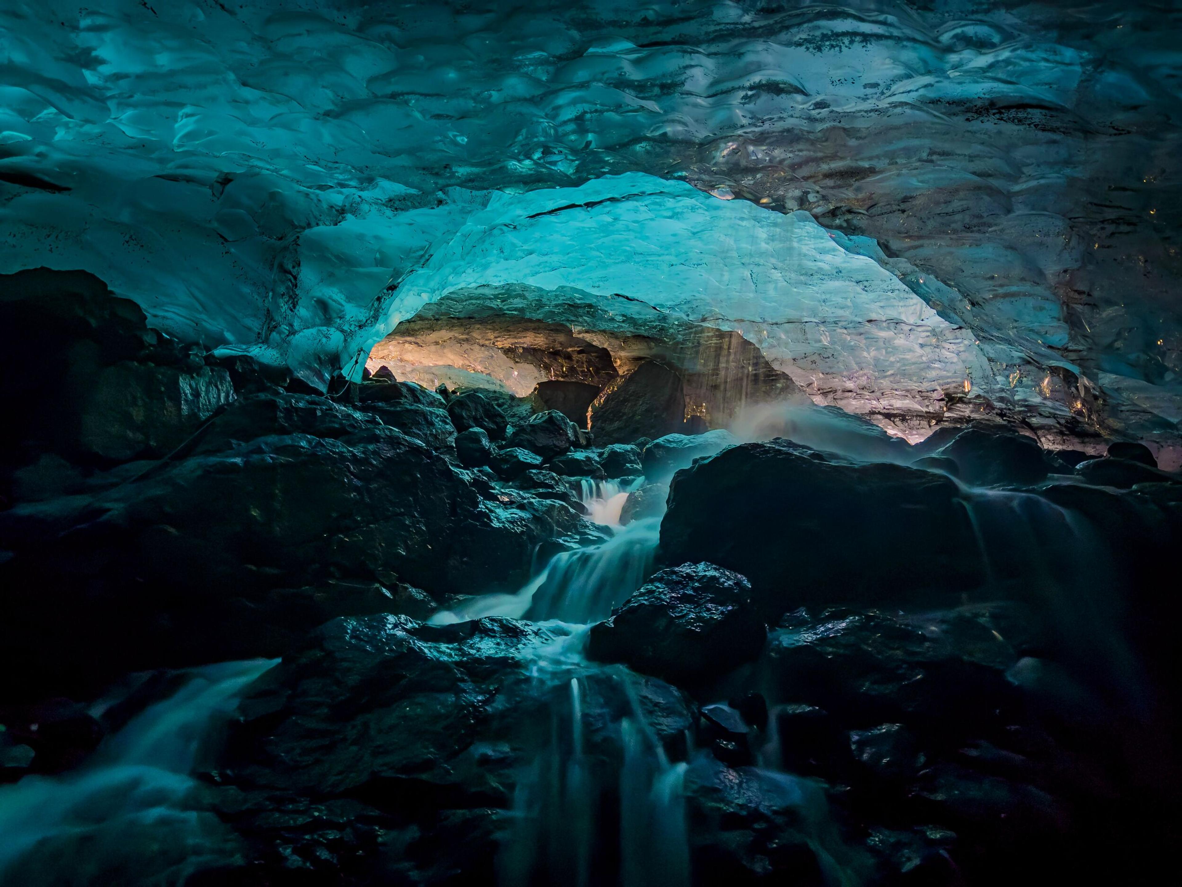 a waterfall is coming out of an ice cave .