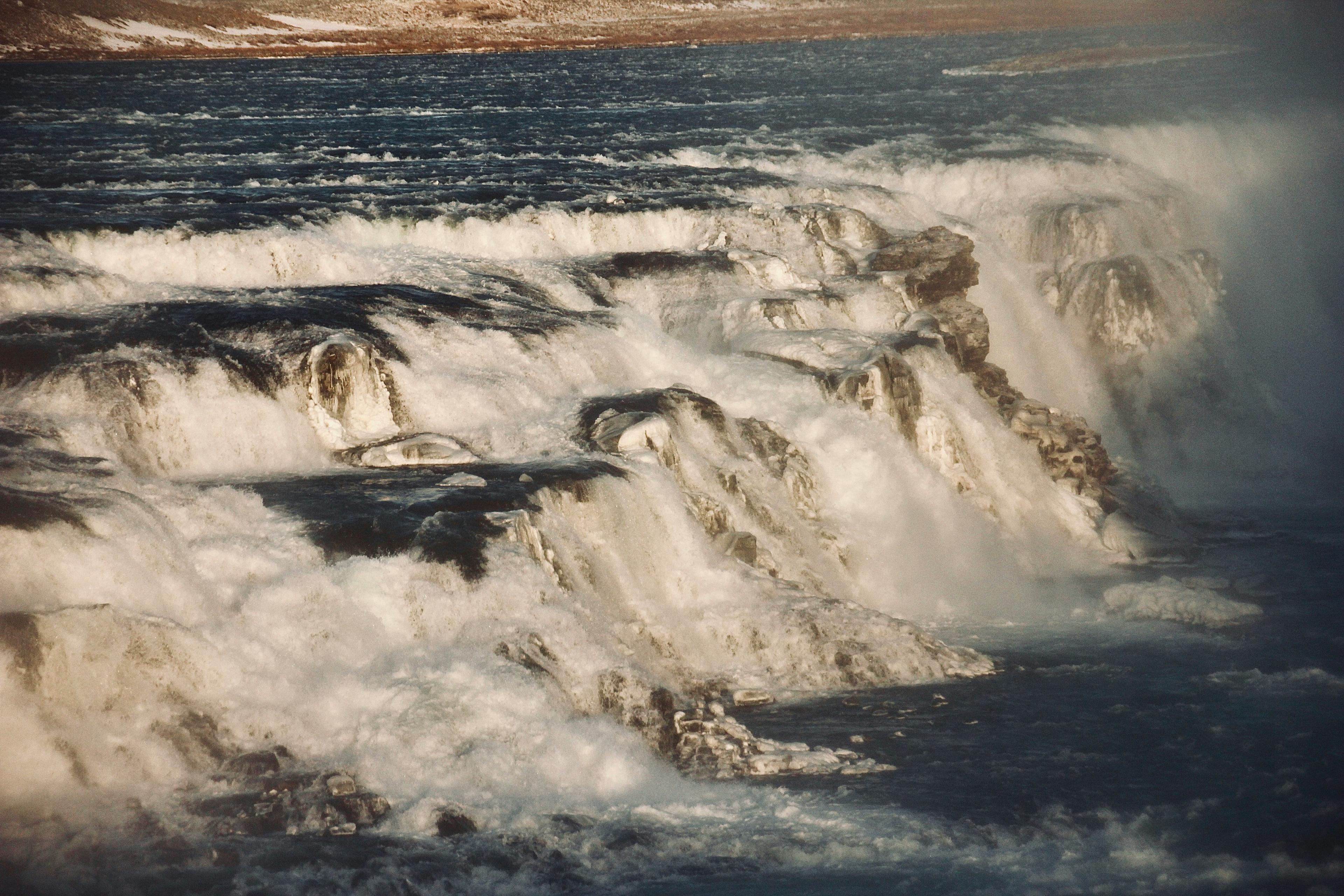 A close-up view of a cascading waterfall, its waters frothing and flowing rapidly over the rocks, likely a section of a larger falls in Iceland.