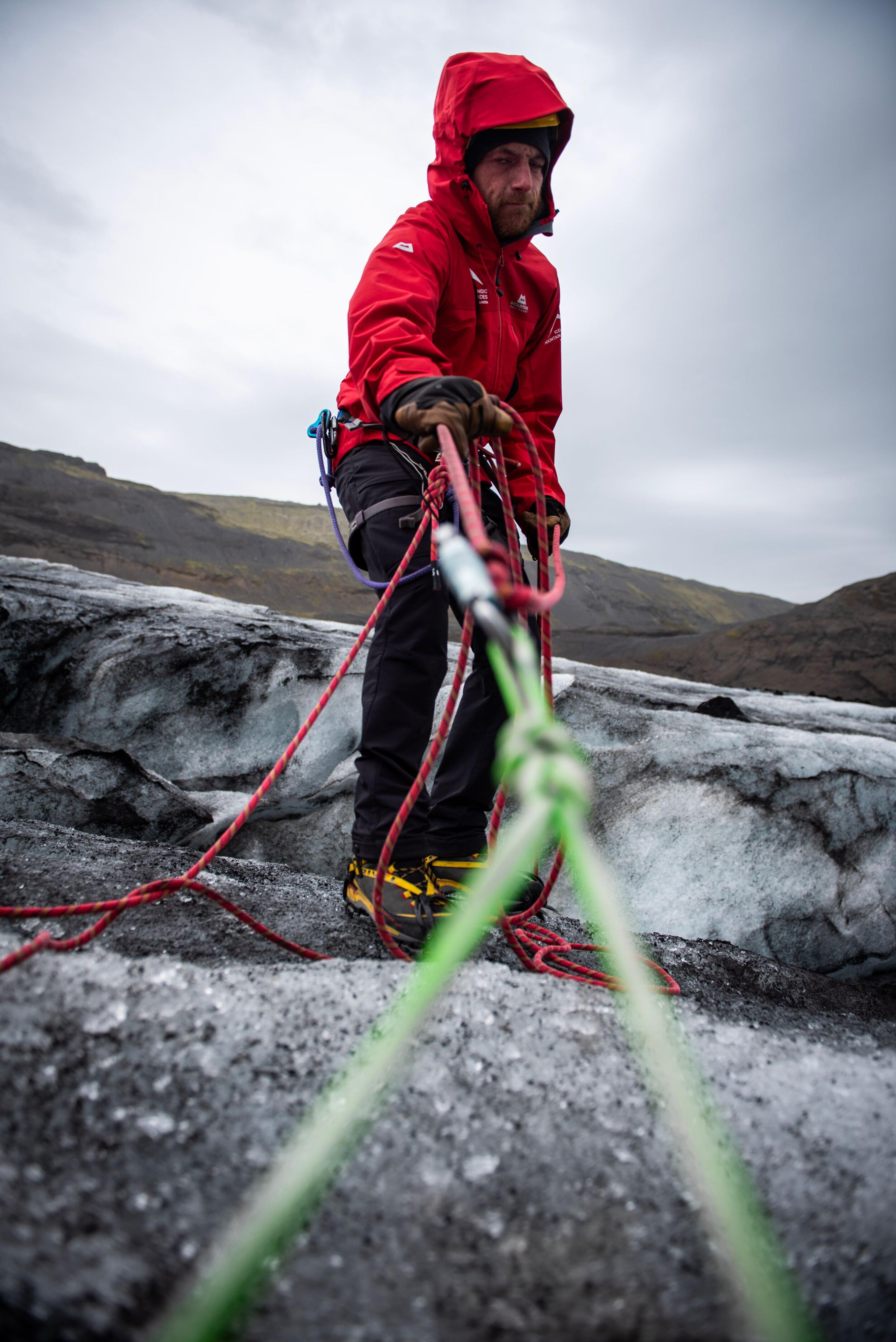a man in a red jacket is holding a green rope
