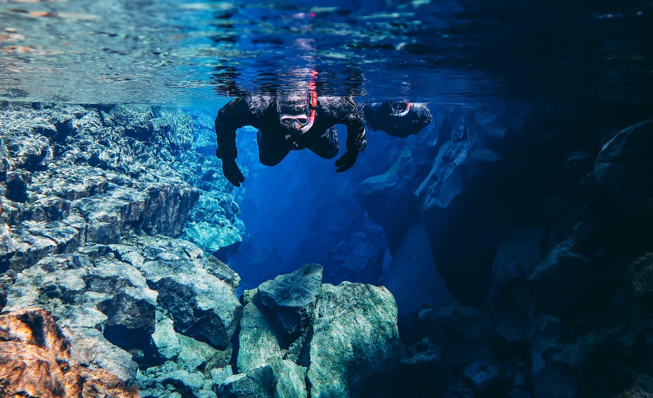 A person snorkeling in the pristine waters of Silfra lake in the Þingvellir National Park in Iceland.