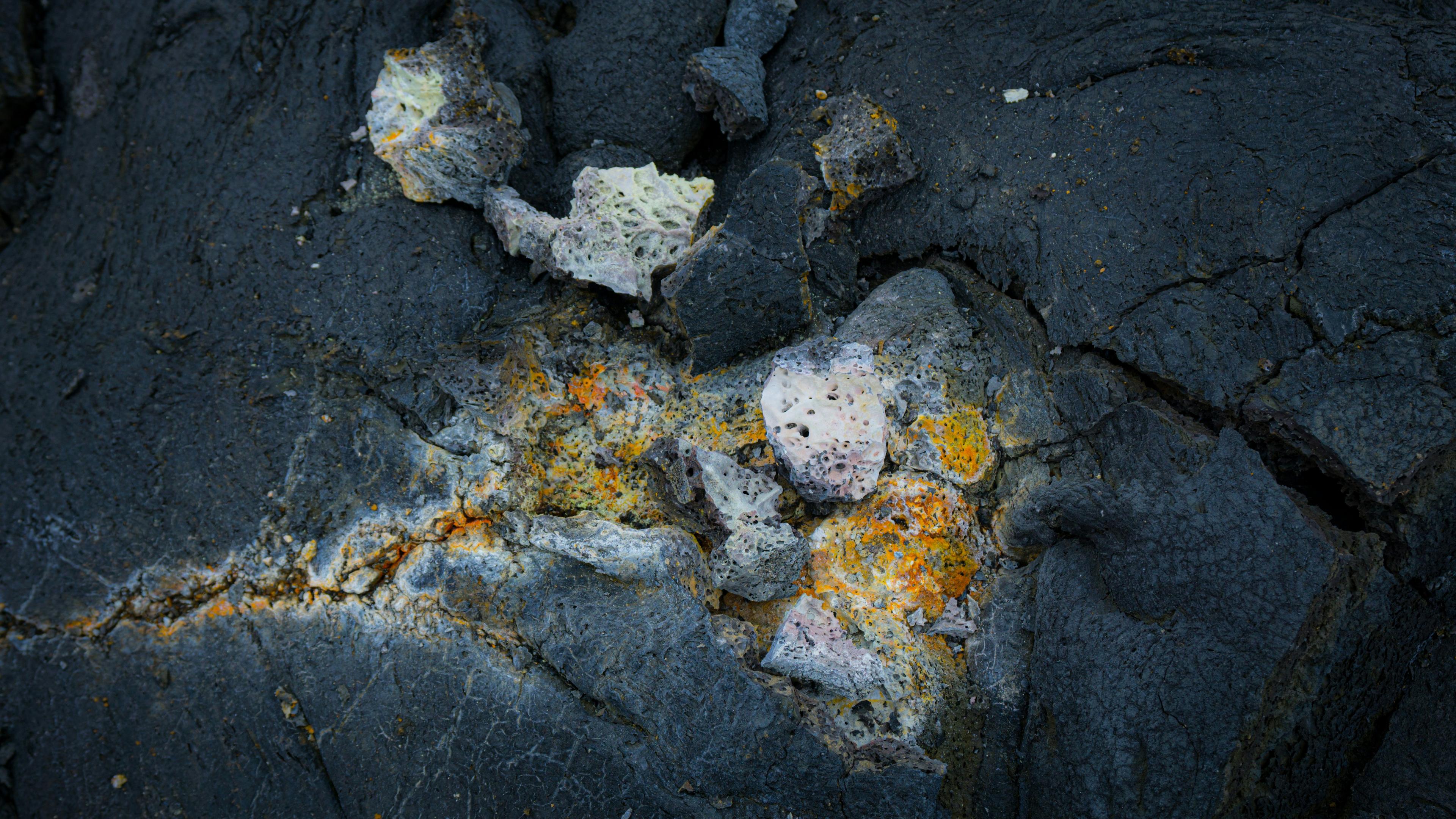 Close-up of textured volcanic rocks formed from the recent Iceland eruption, showcasing orange mineral deposits