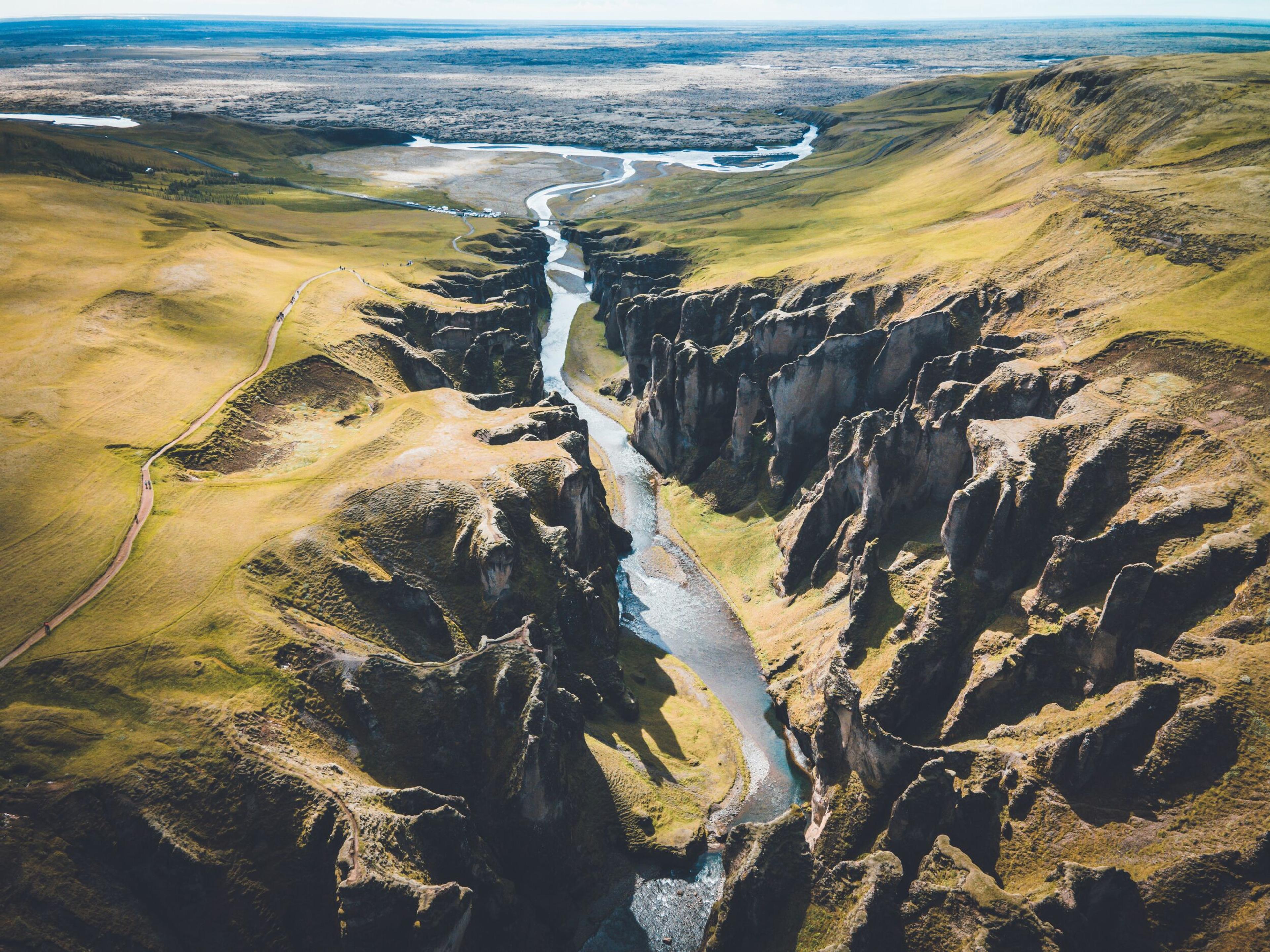 Aerial view of a river flowing through a deep, grassy canyon with steep cliffs.