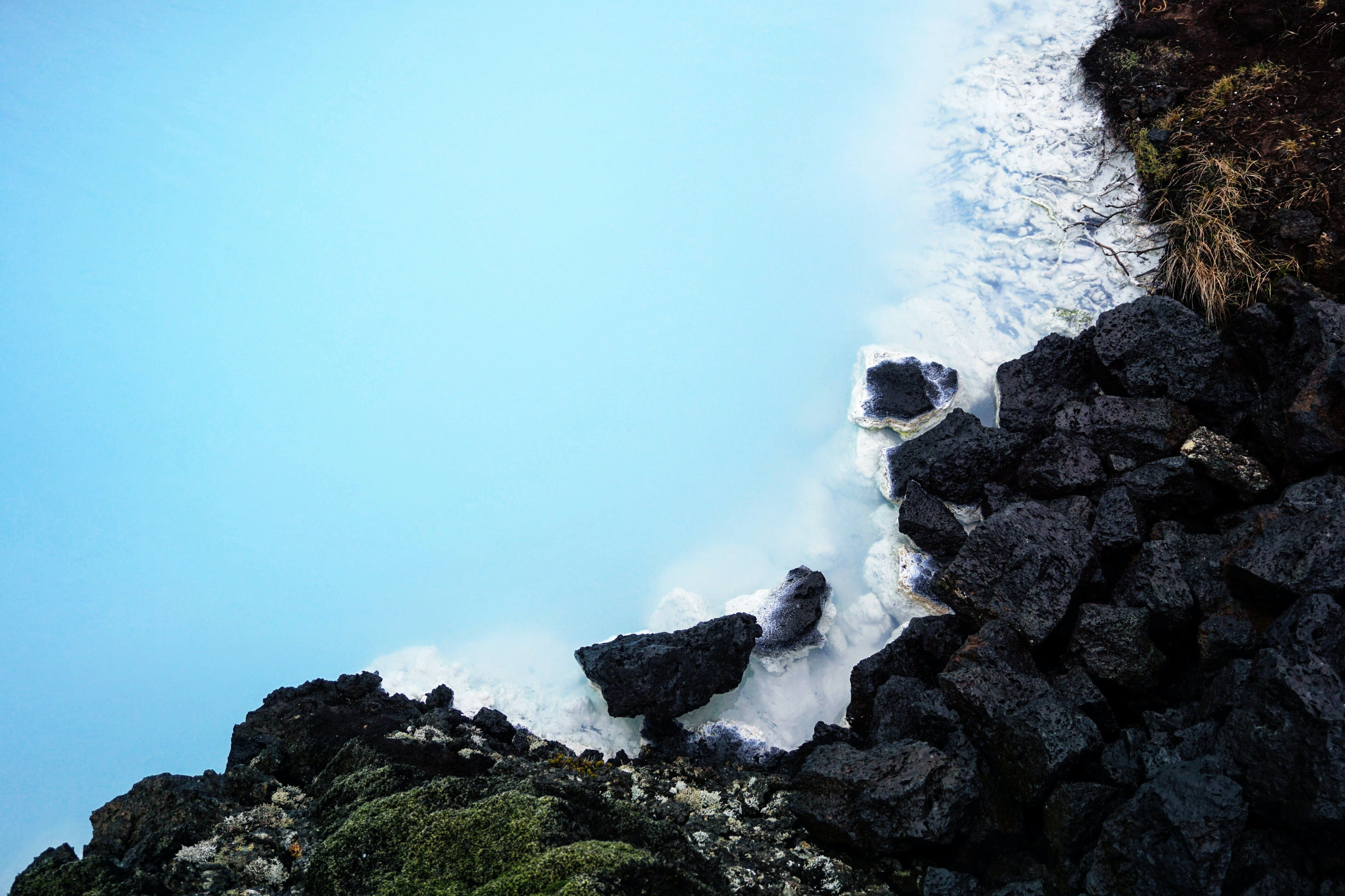 Striking contrast of black volcanic rocks against the milky-white, silica-rich waters and vibrant green moss