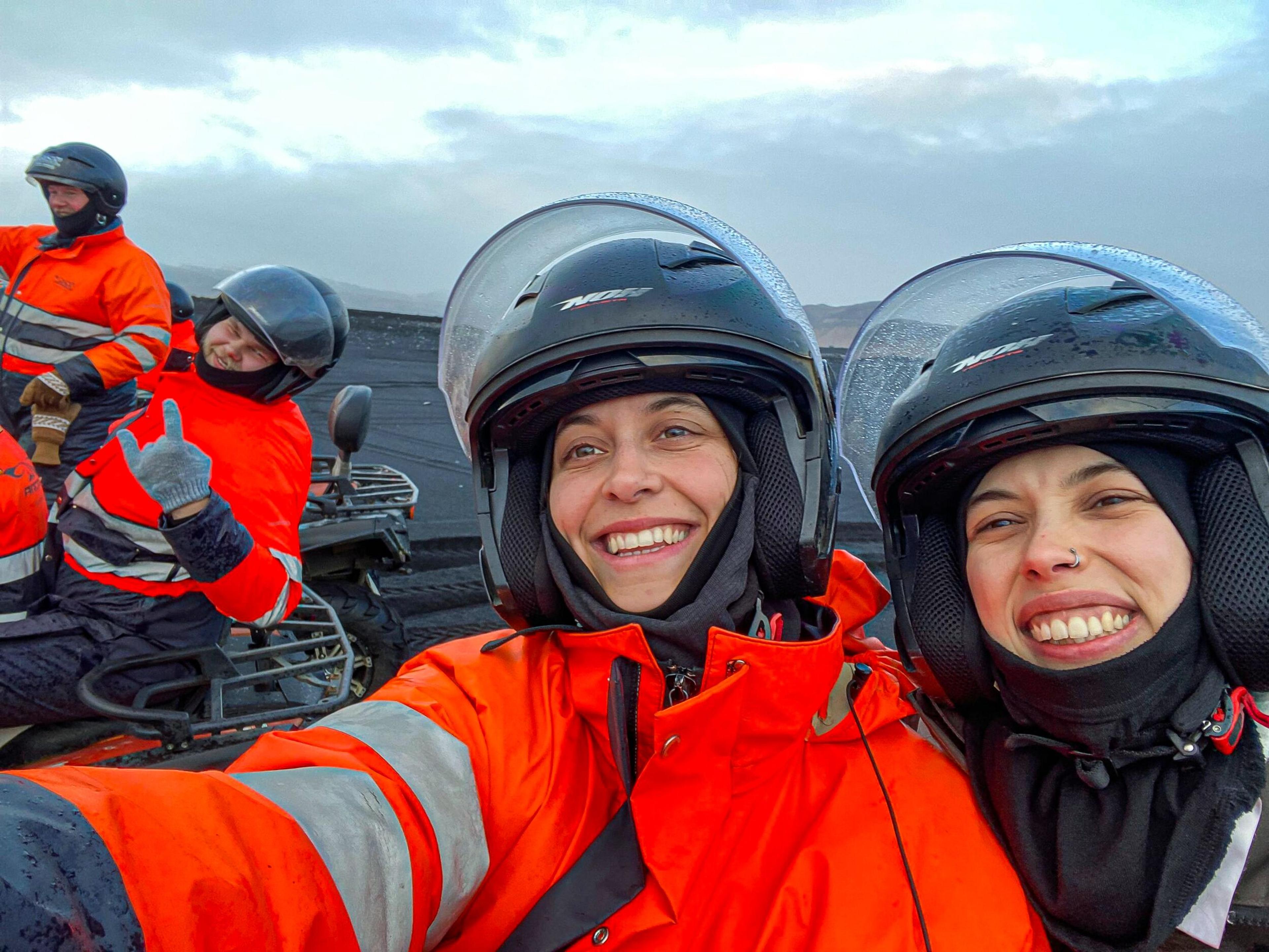 Two people in orange safety suits and helmets taking a selfie.