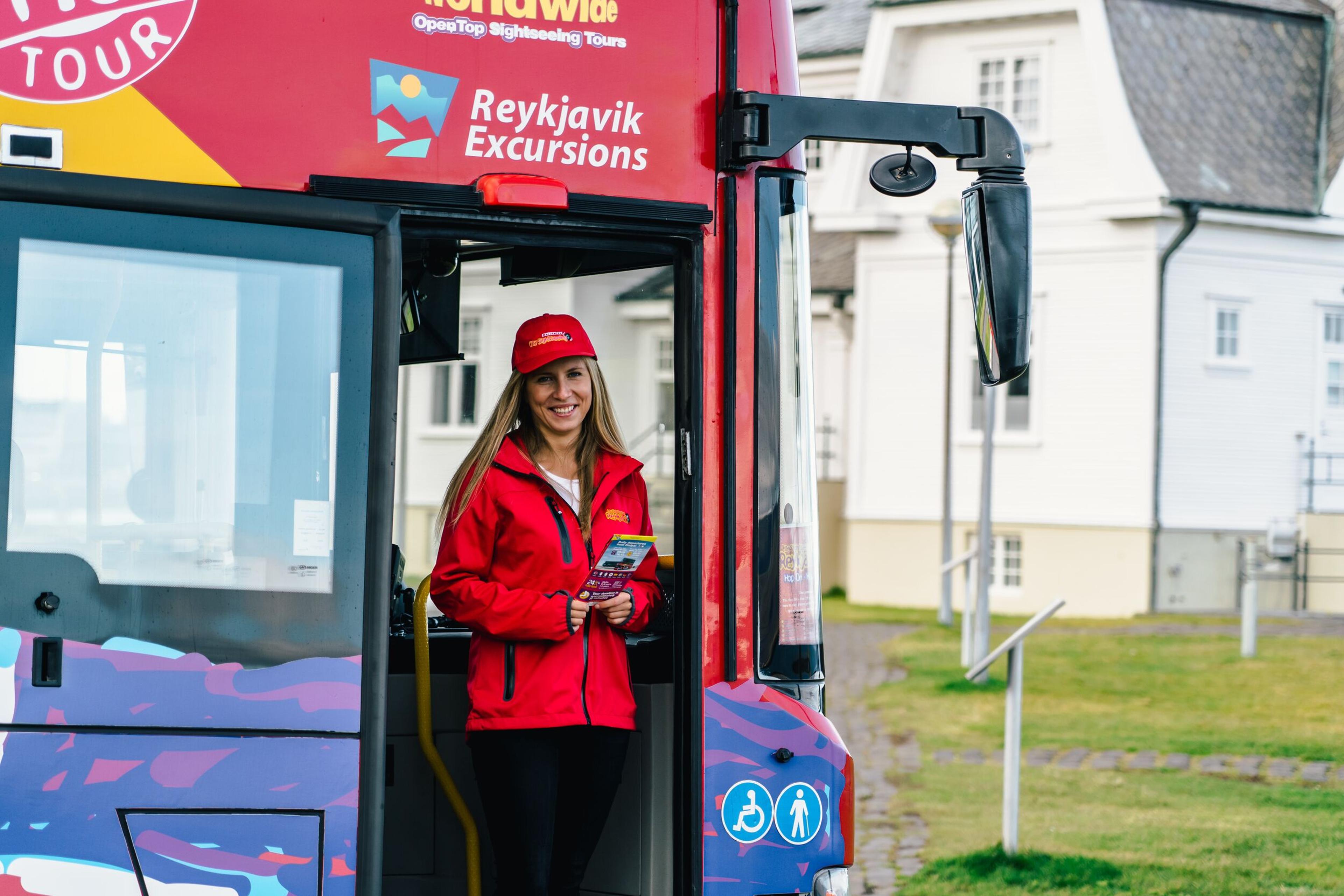 A guide standing at the entry of a Hop-on Hop-off bus greeting people.