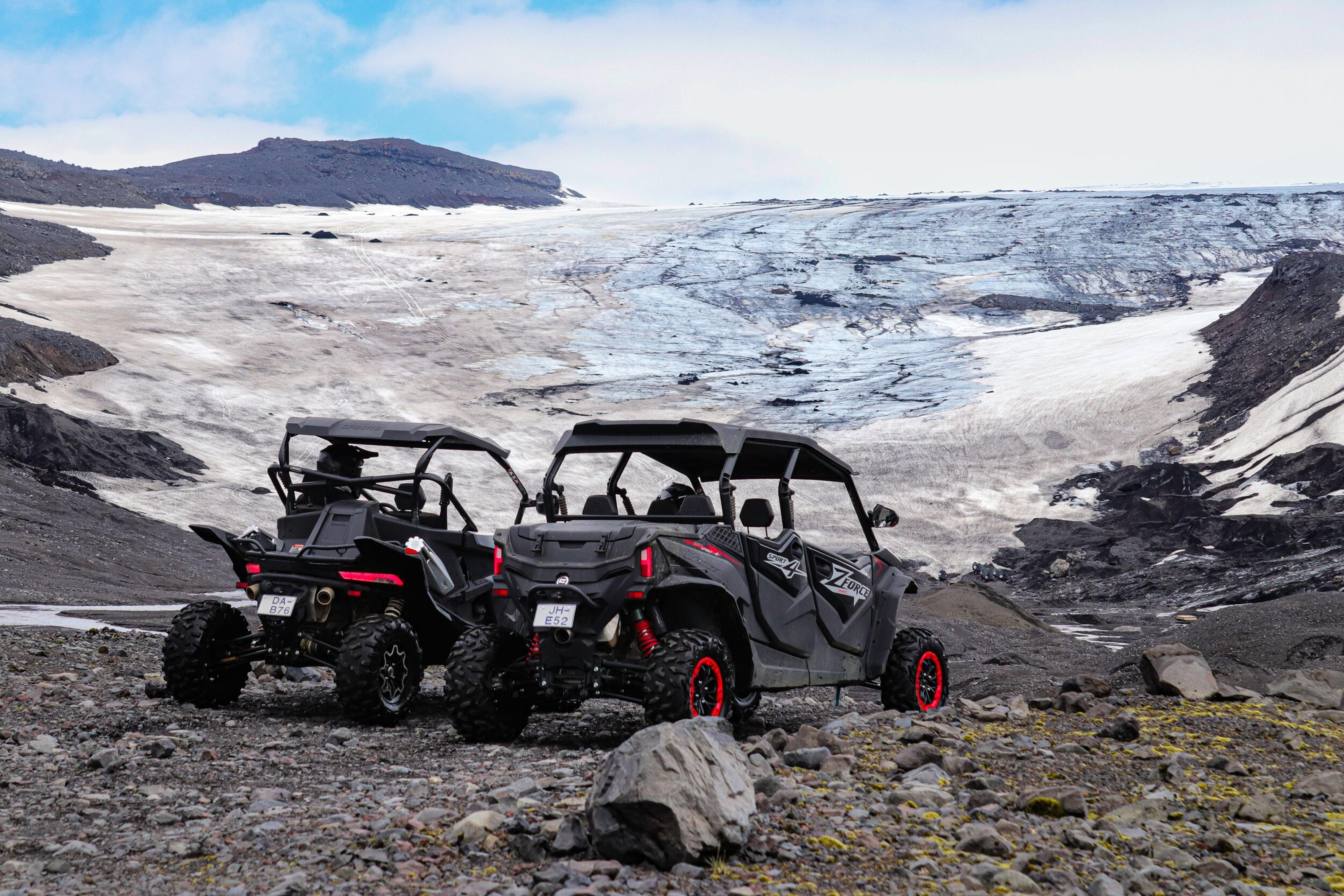 Off-road buggy driving on rocky terrain near a snow-covered slope on the South Coast of Iceland.