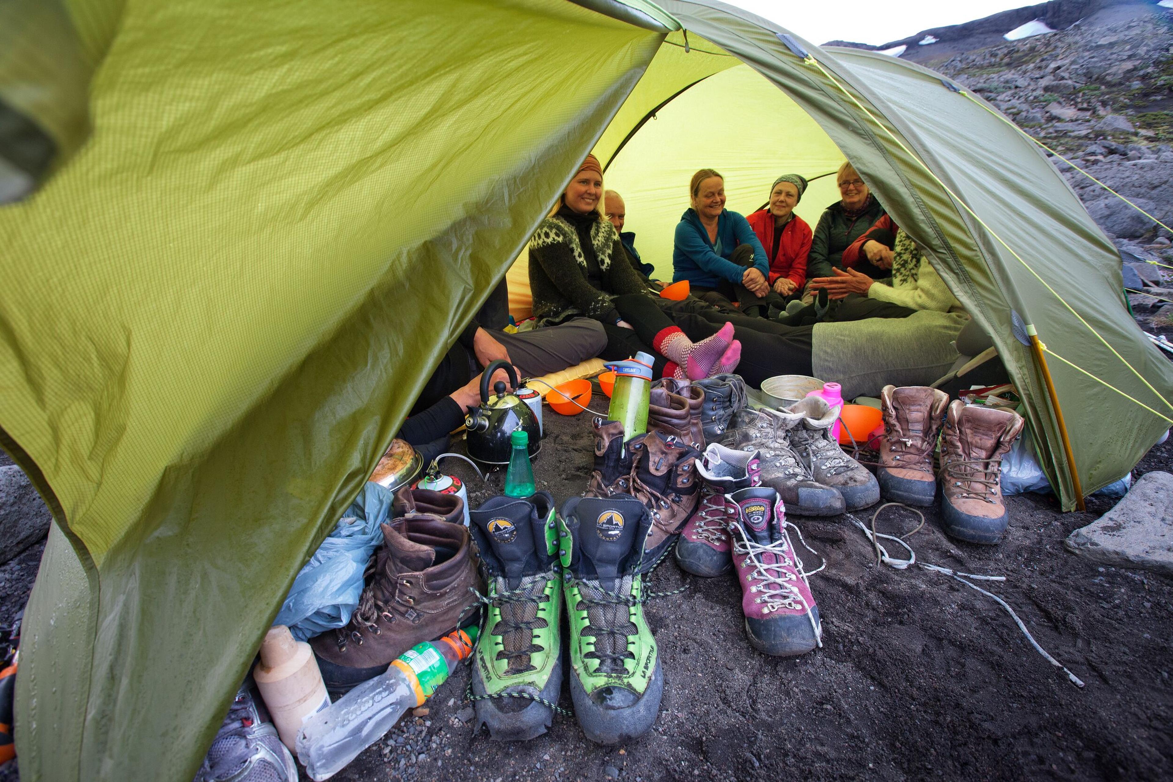 Hiking group in a tent, hiking boots in foreground