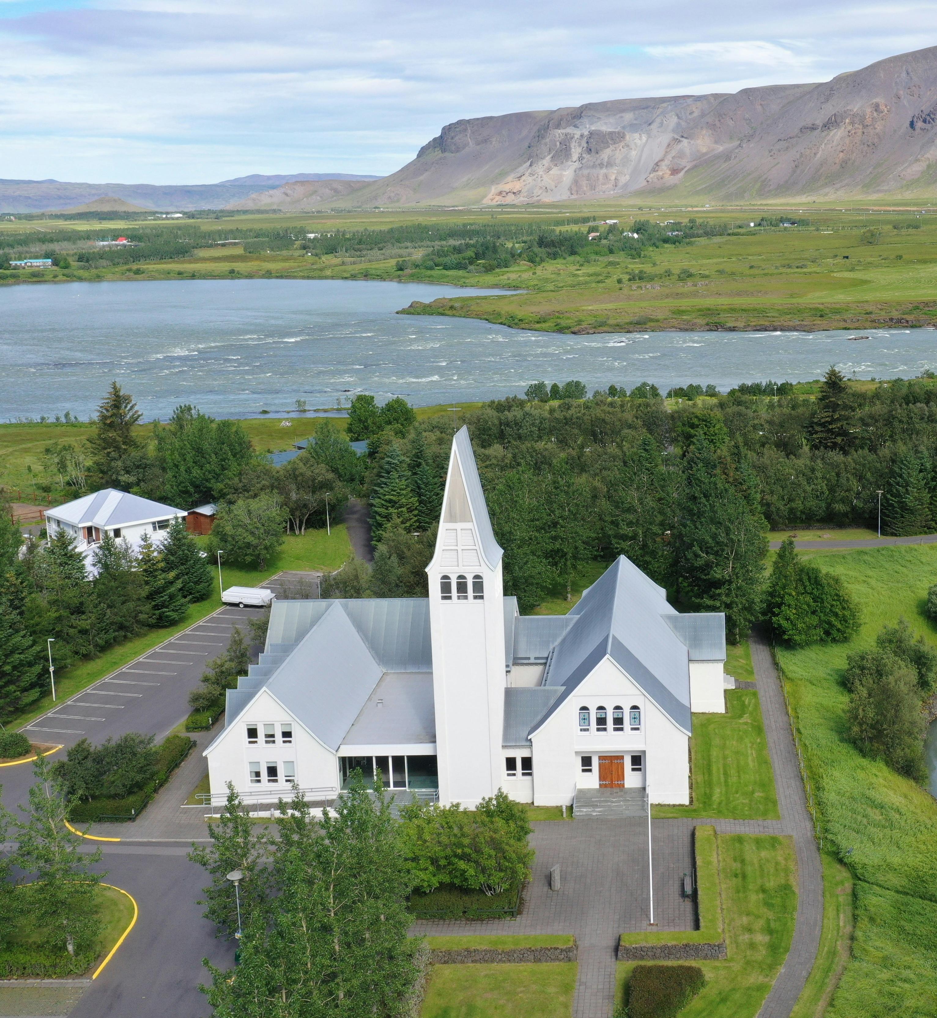 Selfoss Church in Iceland, a modern white building with a distinctive triangular design and a tall, narrow steeple.