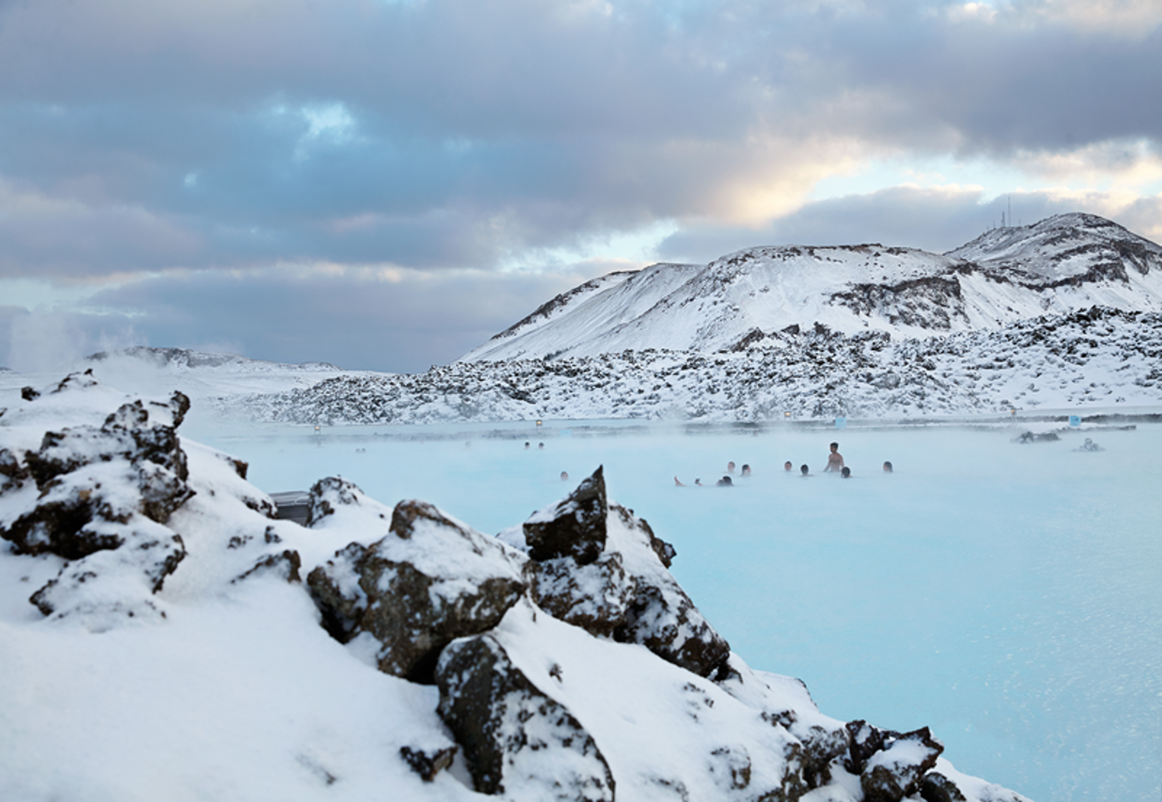 Blue Lagoon's geothermal waters contrasting with surrounding snow-covered landscape in winter.