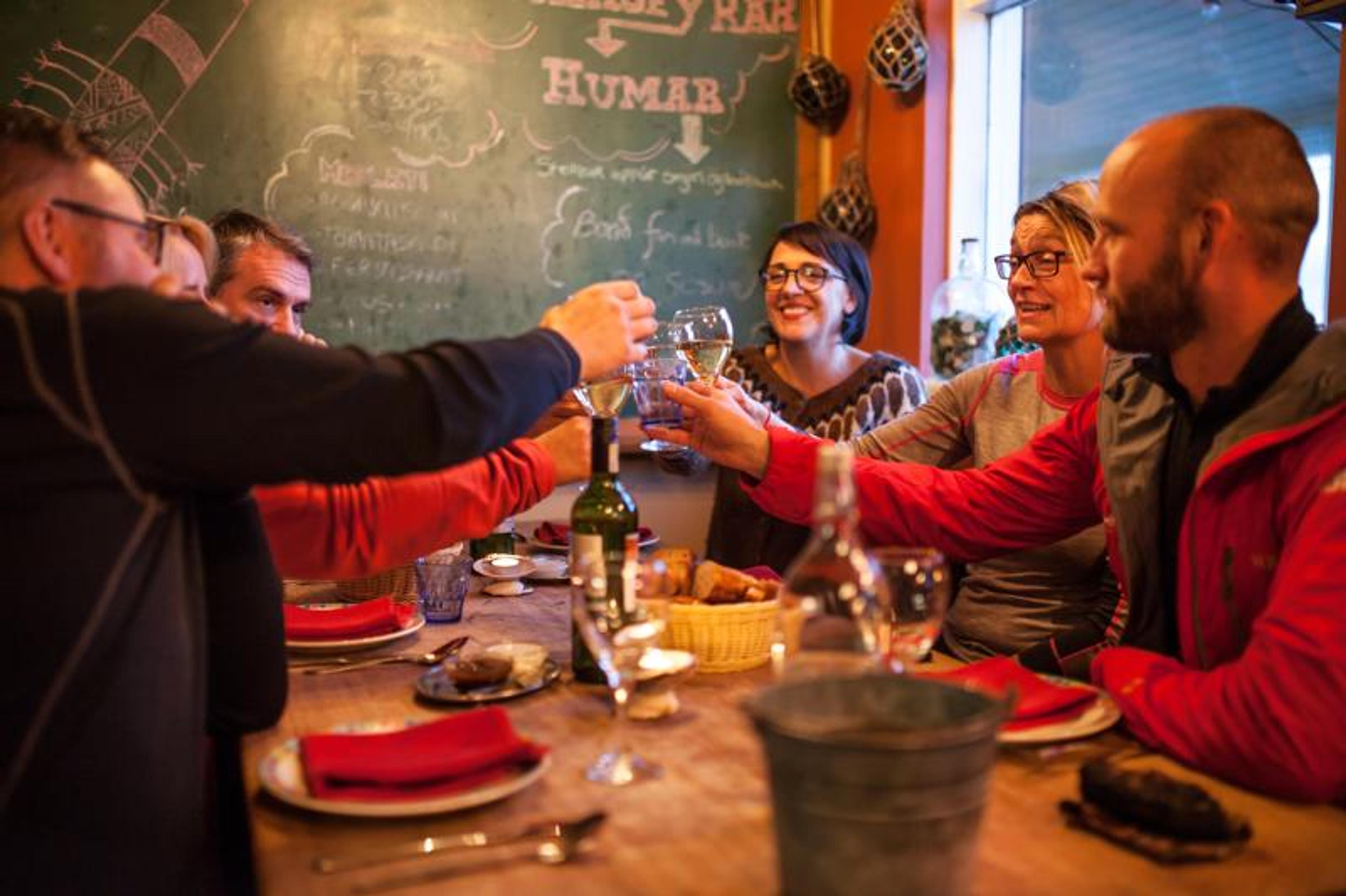 Six people toast with wine glasses around a table.