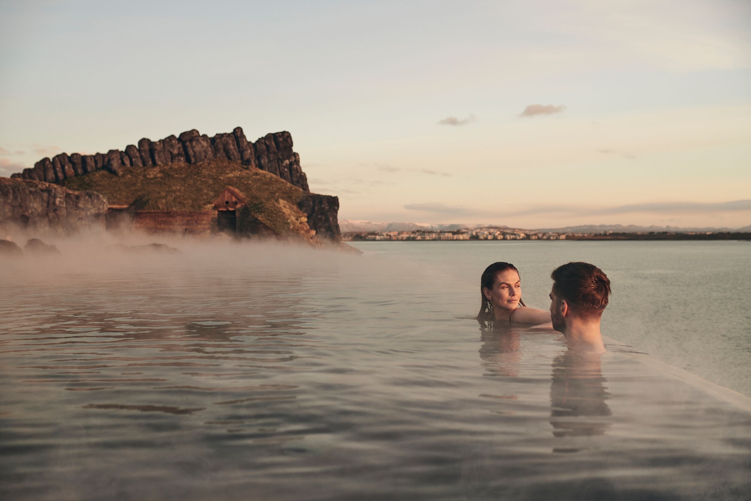 A couple unwinding at the edge of Sky Lagoon's infinity pool