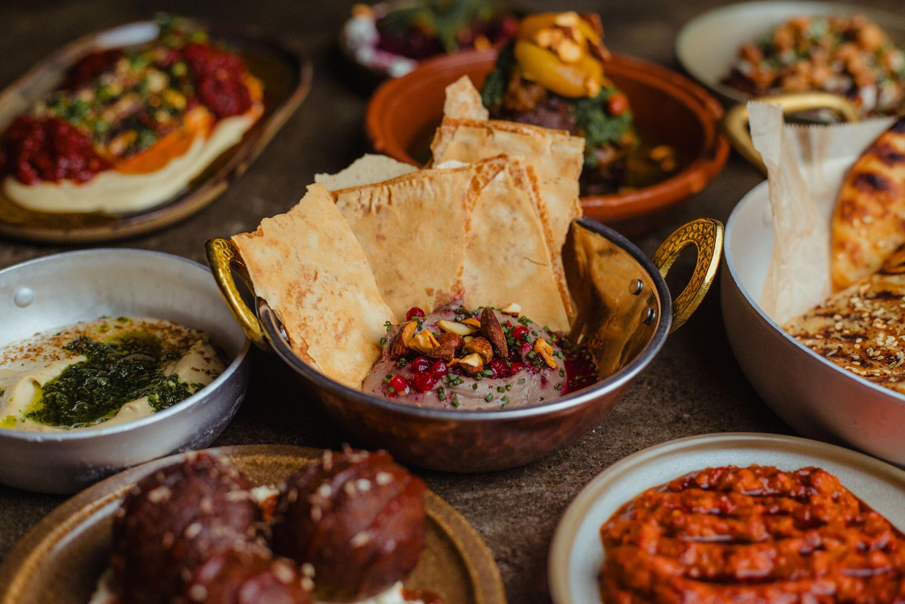 A vibrant spread of Middle Eastern dips, pita bread, and various dishes on a rustic table.