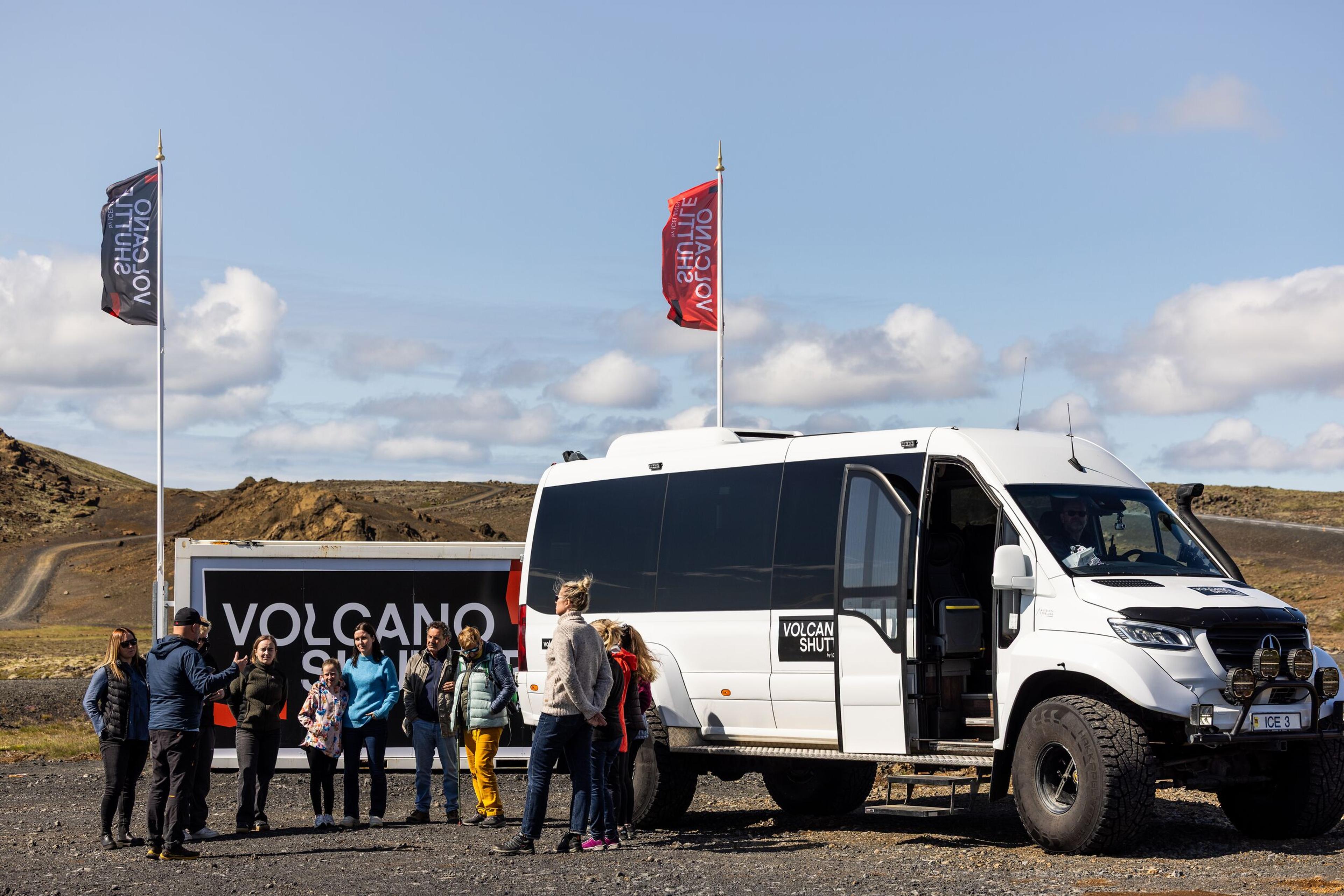a group of people are standing in front of a volcano shuttel .