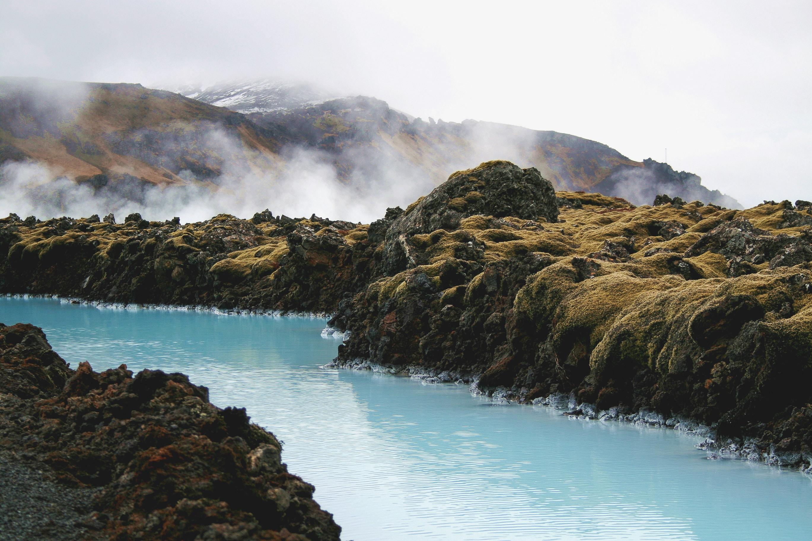 Milky blue water winding through a moss-covered lava field.