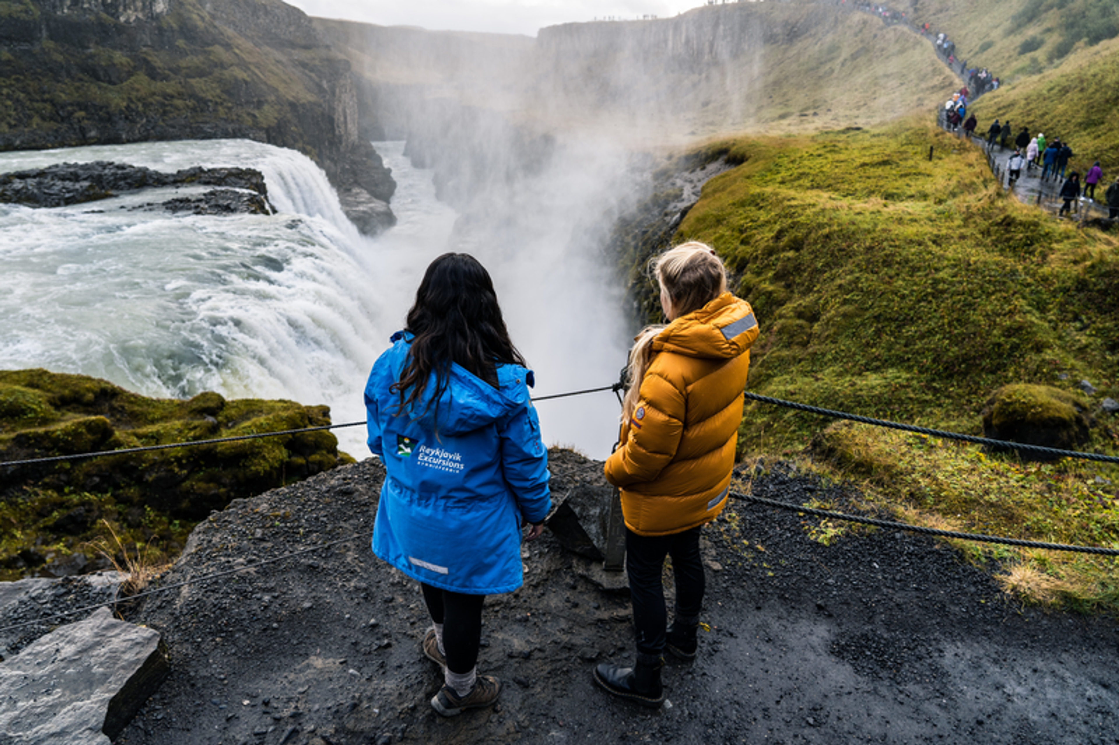 two people are looking at a waterfall and one of them is wearing a jacket that says facebook adventures