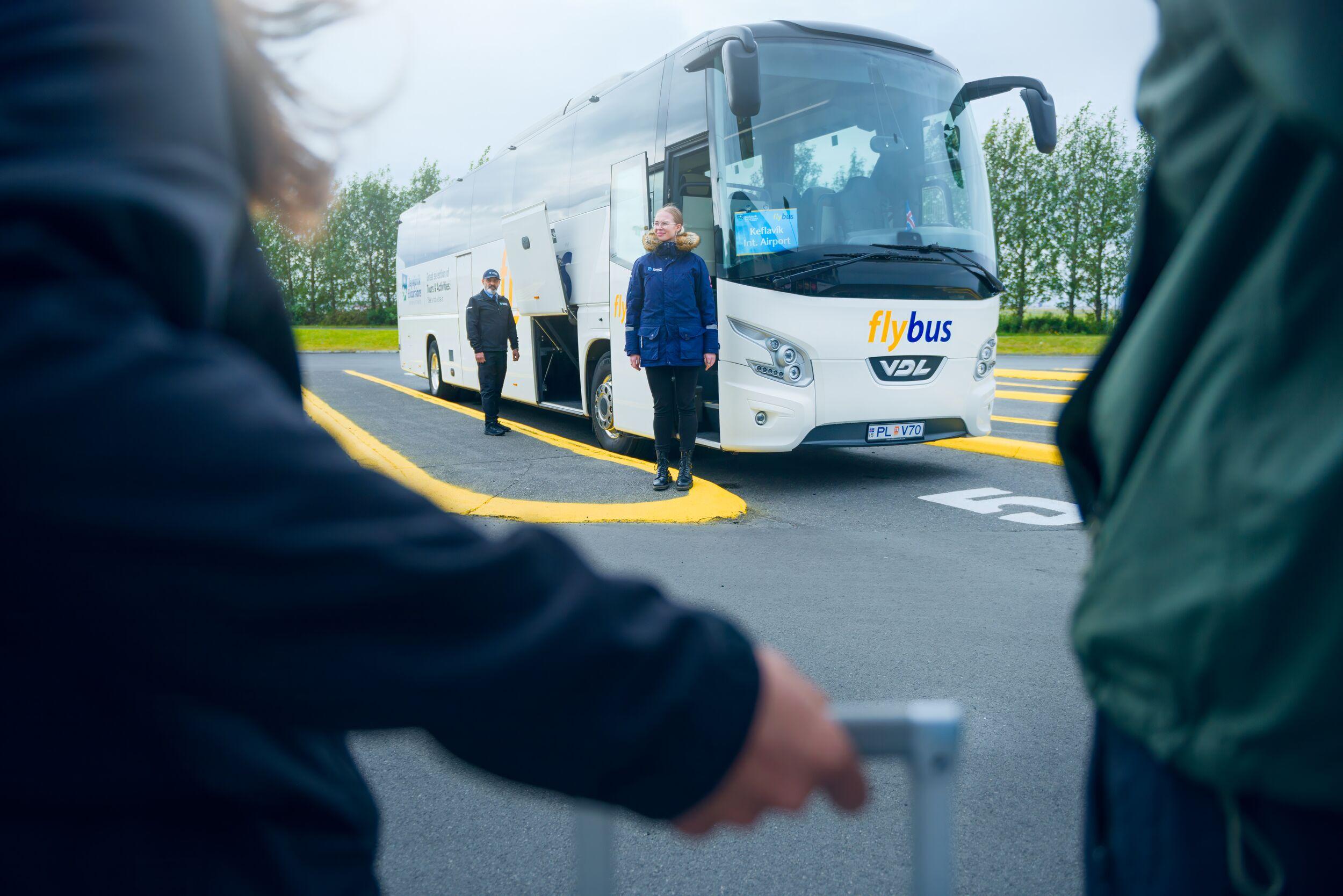 Passangers waiting to board on a flybus bus at BSI terminal in Reykjavík. White bus in the background.