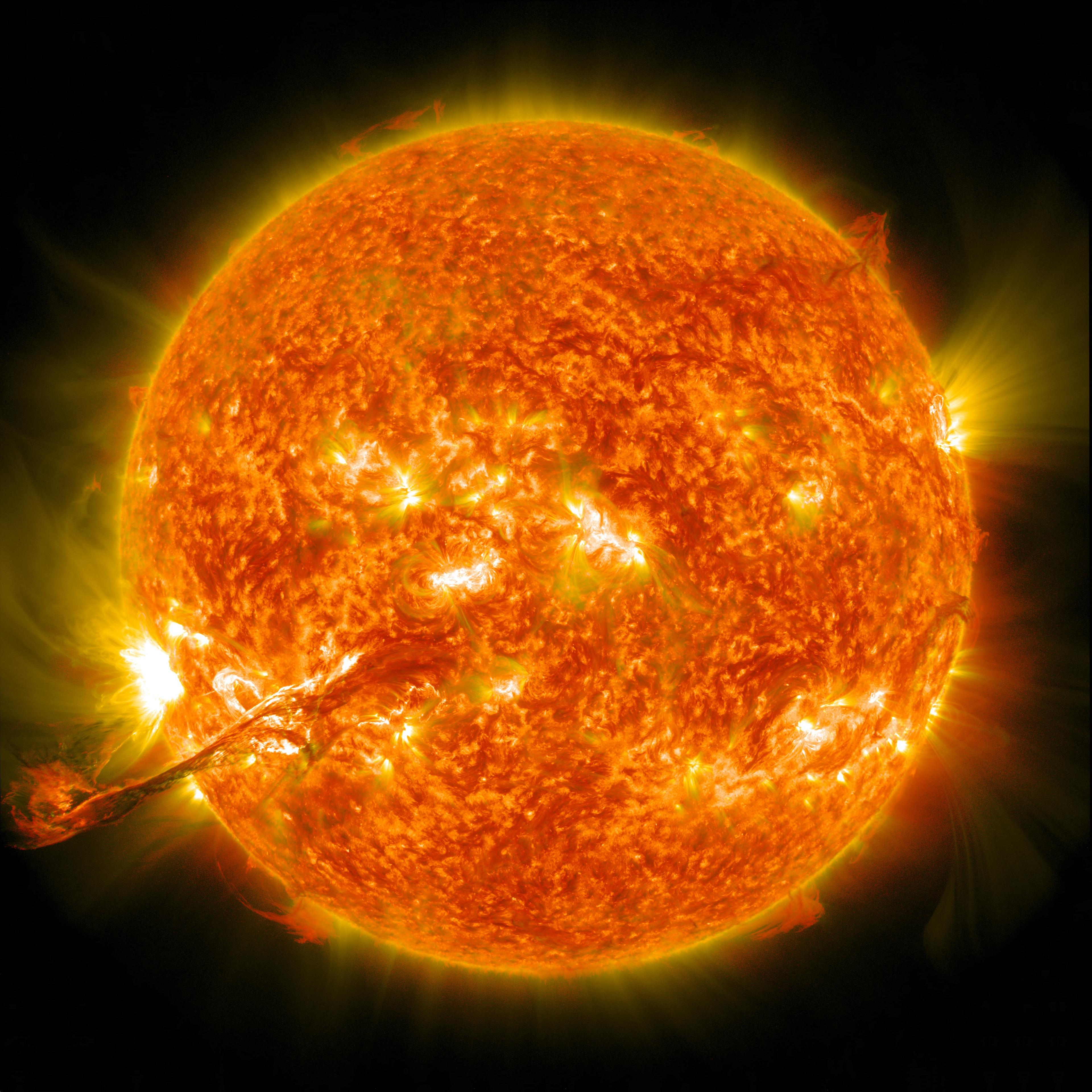A vibrant image of the Sun showcasing dynamic solar activity, with bright flares and prominences extending from the surface, set against the dark backdrop of space.
