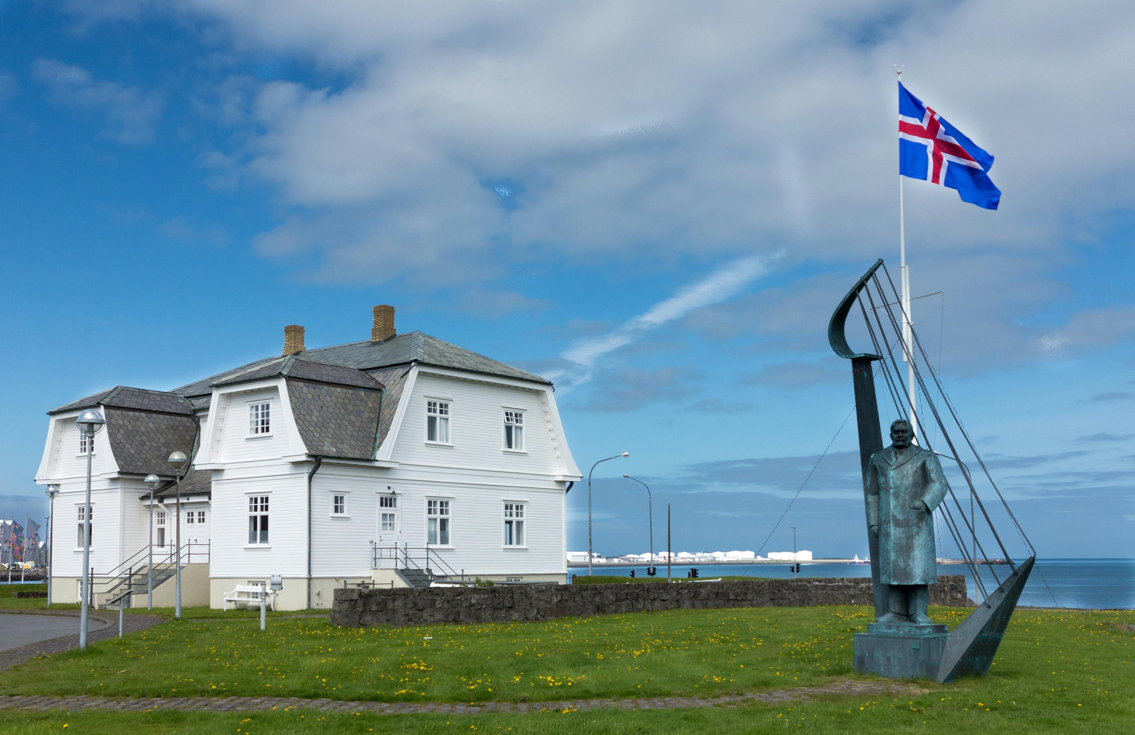 Höfði House in Reykjavik, a historic white building with an Icelandic flag and a sculpture in the foreground.