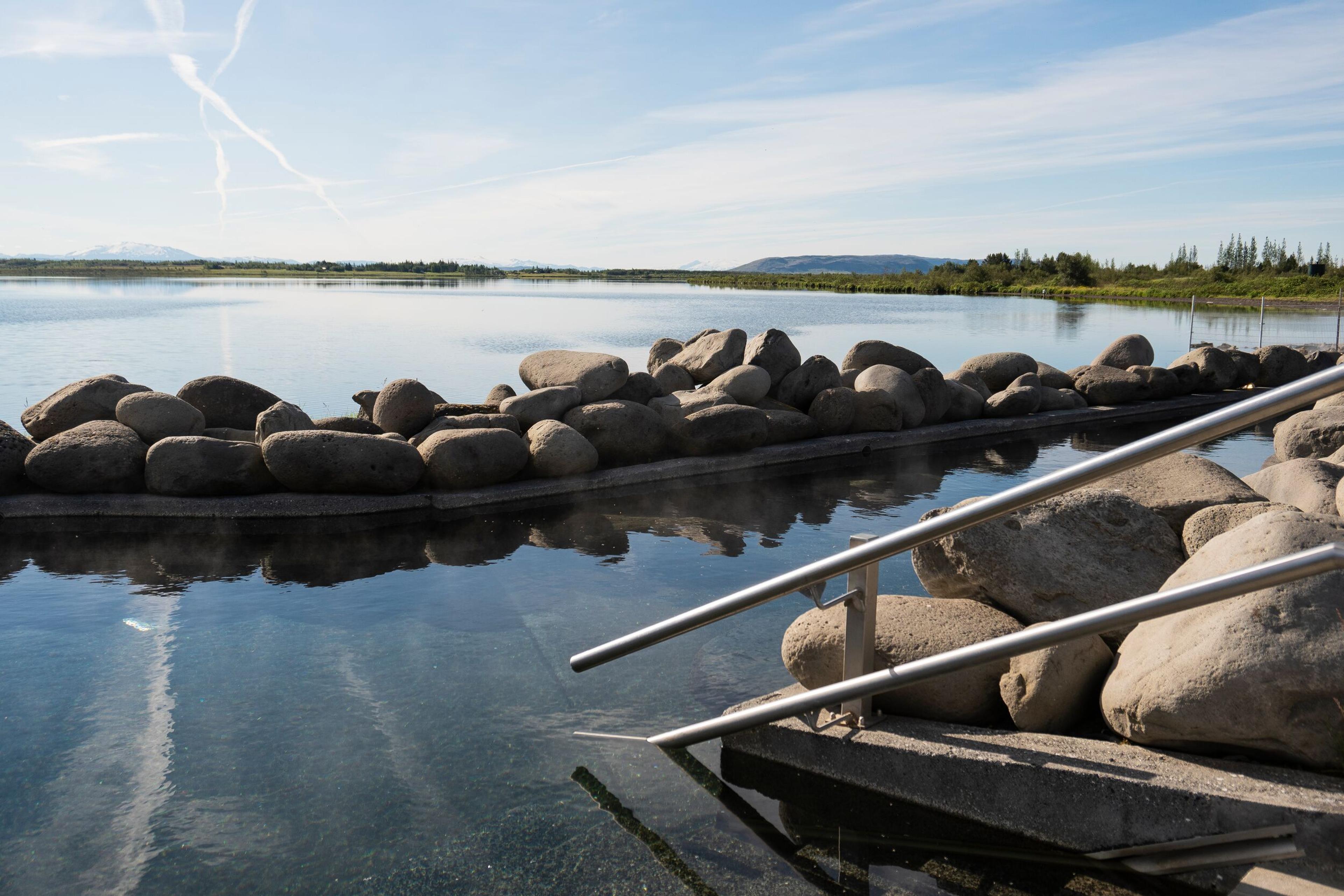 there are stairs leading up to a lake surrounded by rocks .