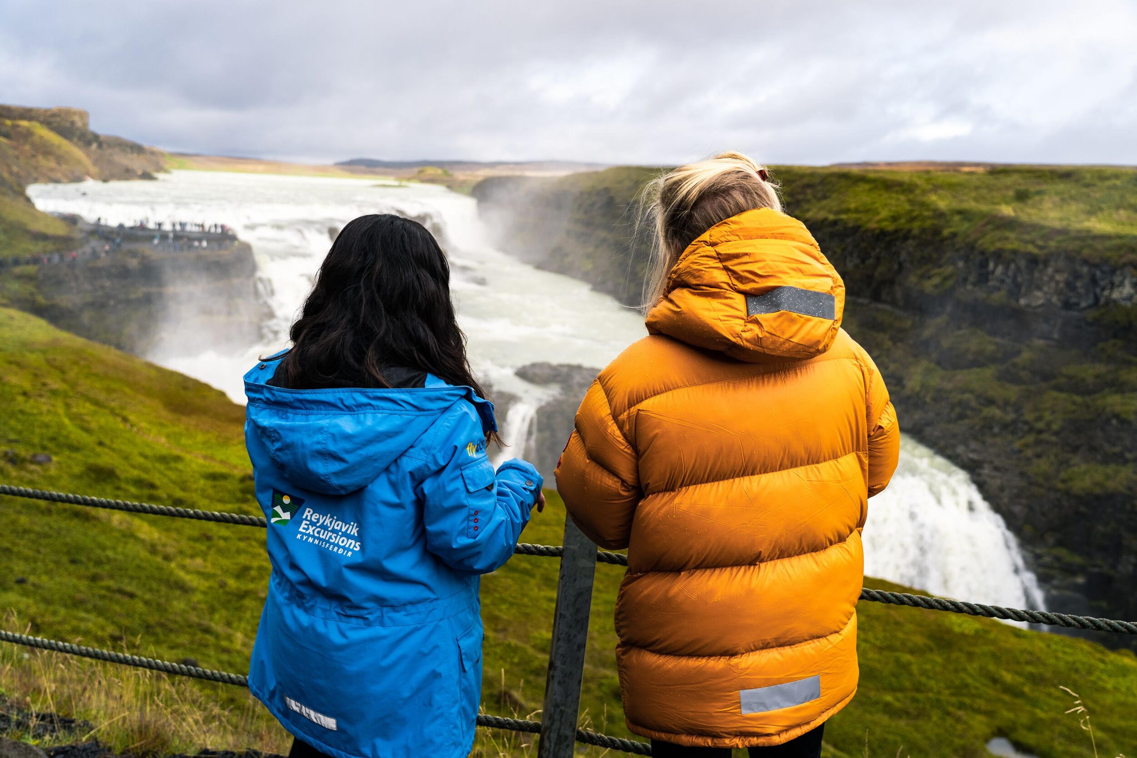 A guide from Reykjavik Excursions passionately explains Gullfoss to a curious tourist. Both captivated by the breathtaking waterfall.