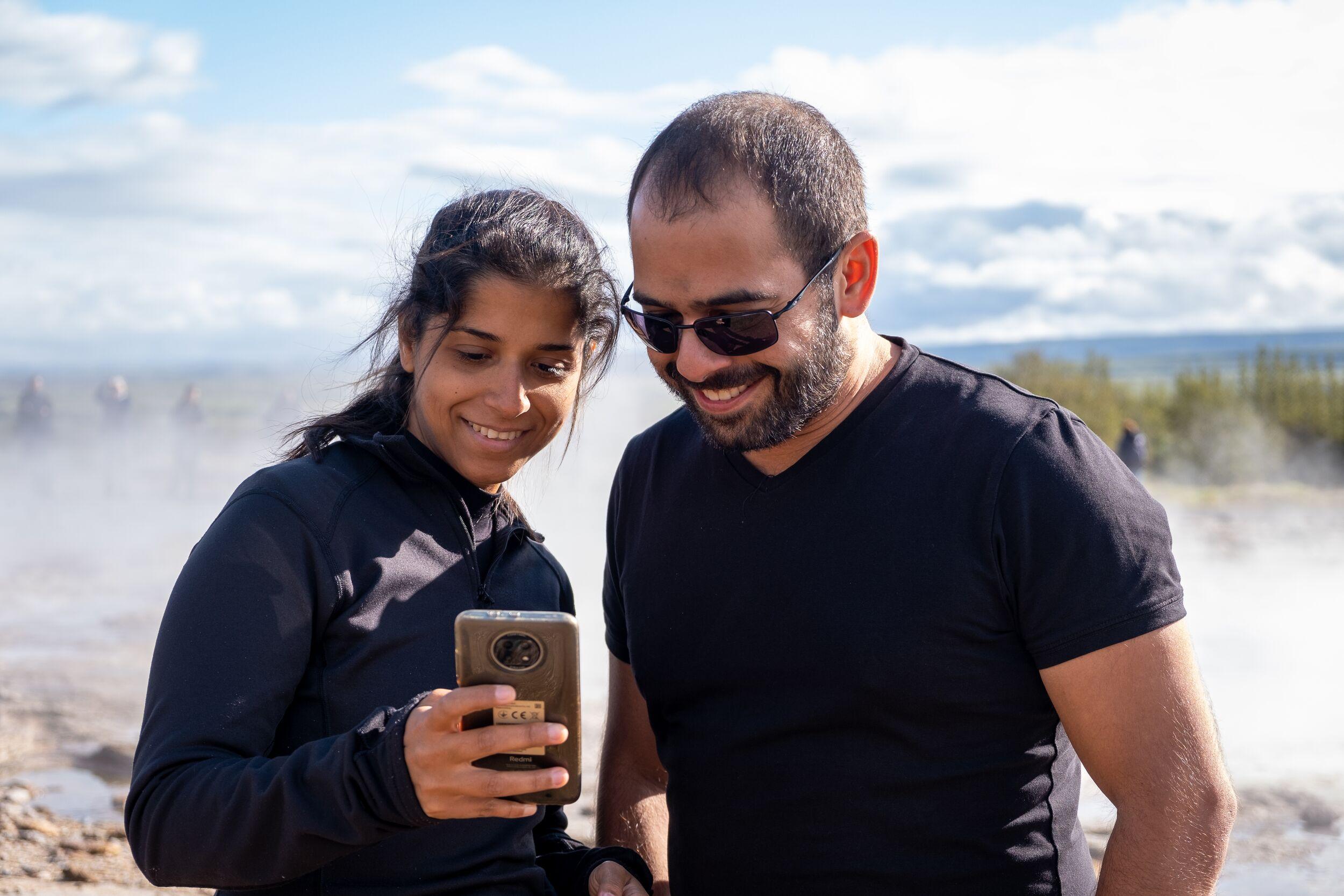 a man and a woman are looking at a cell phone together .