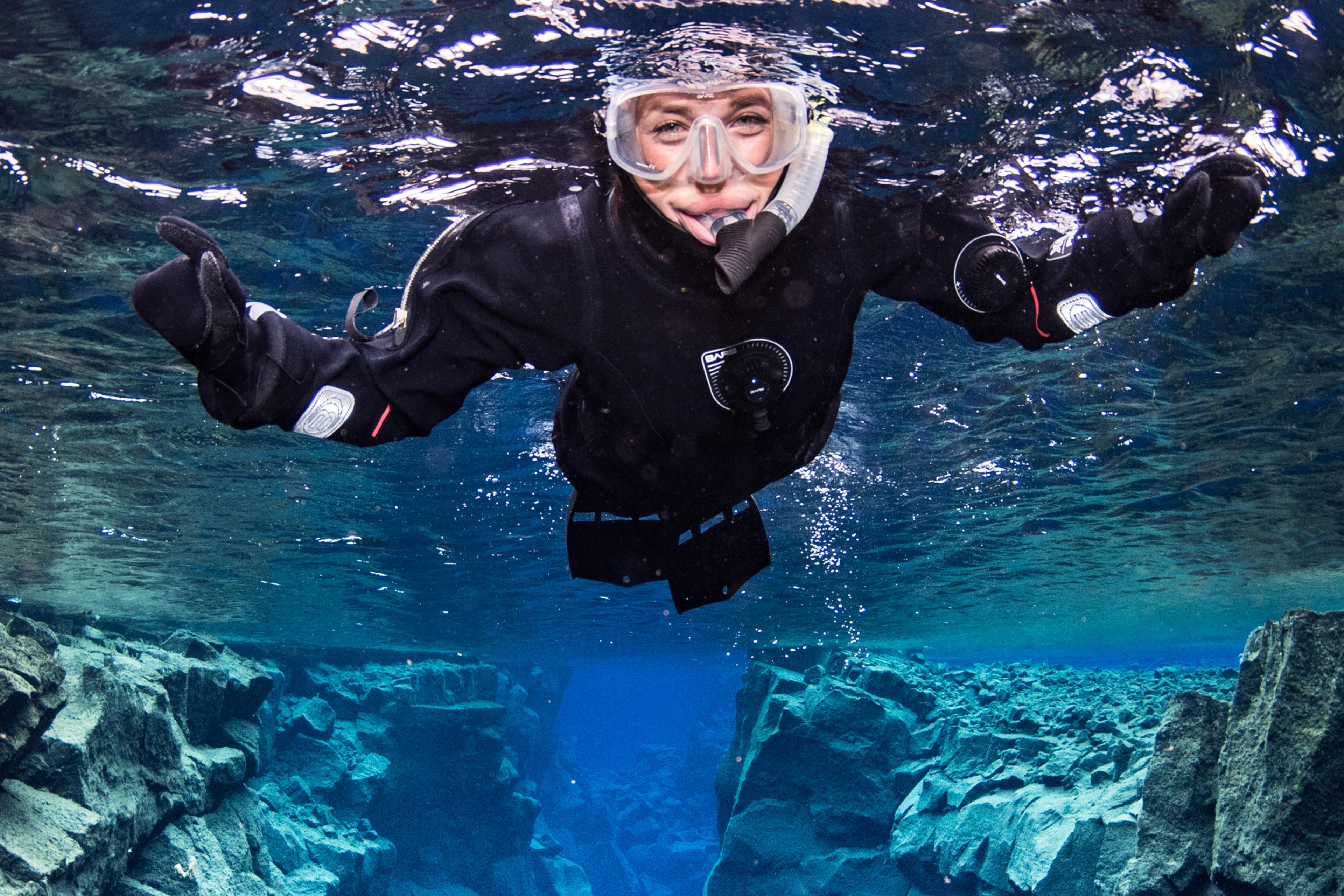 Woman in a dry suit snorkeling in the Silfra water in the Þingvellir National Park, Iceland.