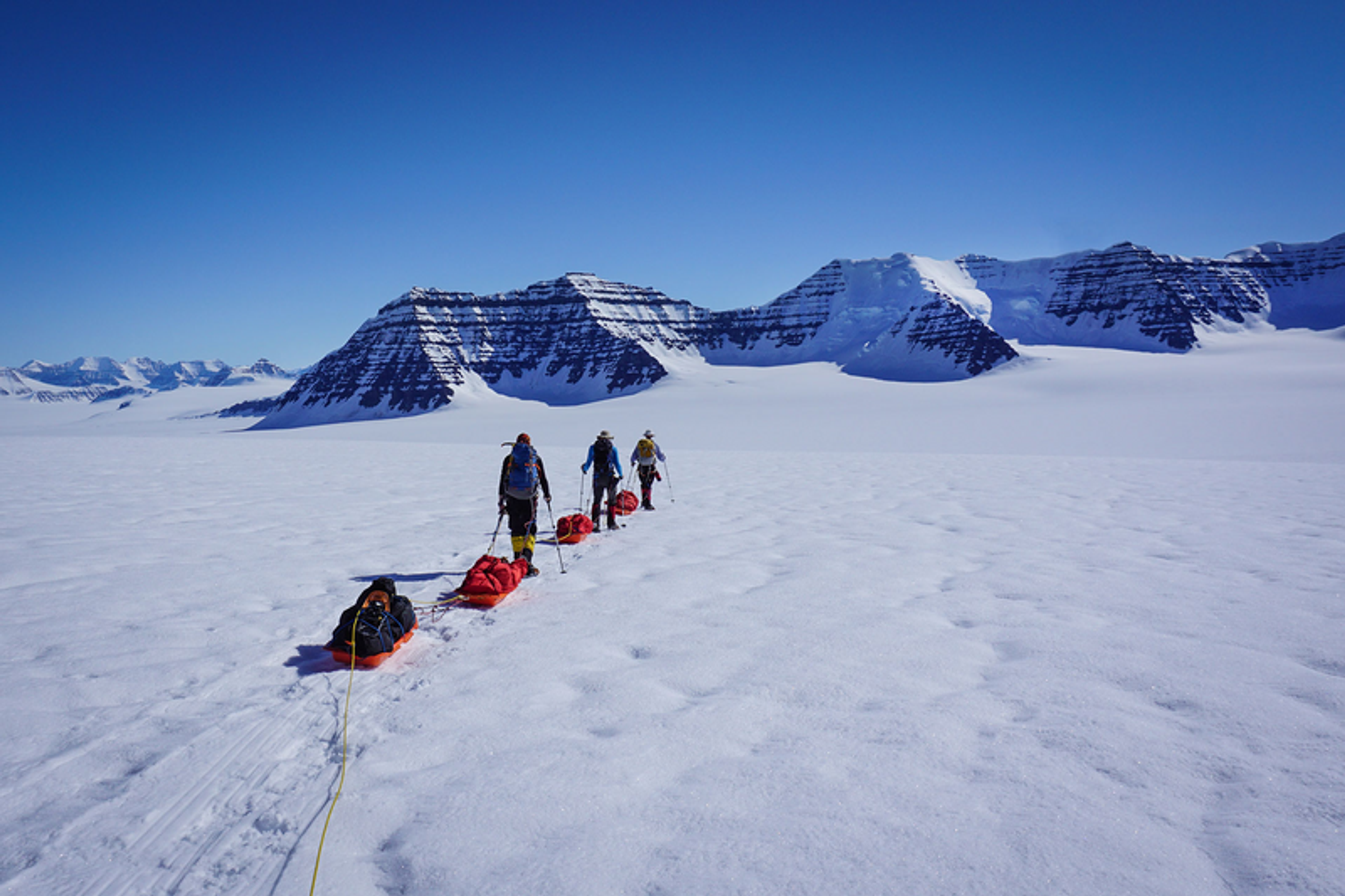 Group of hikers walking on the snow towards a mountain in Greenland