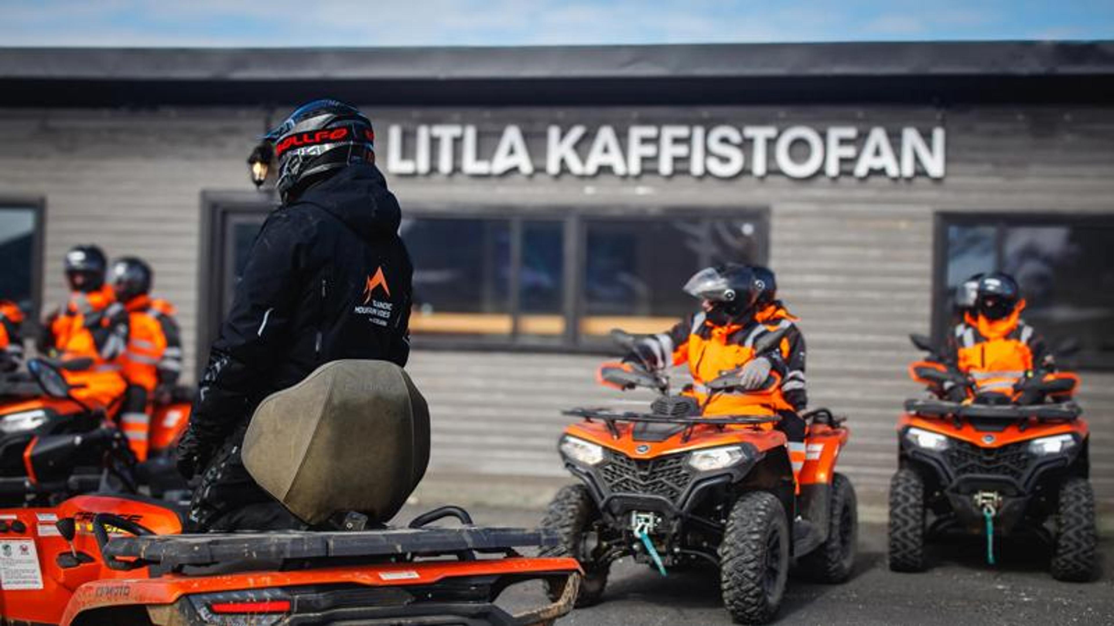 ATV riders in helmets and orange jackets parked outside a building labeled "LITLA KAFFISTOFAN".