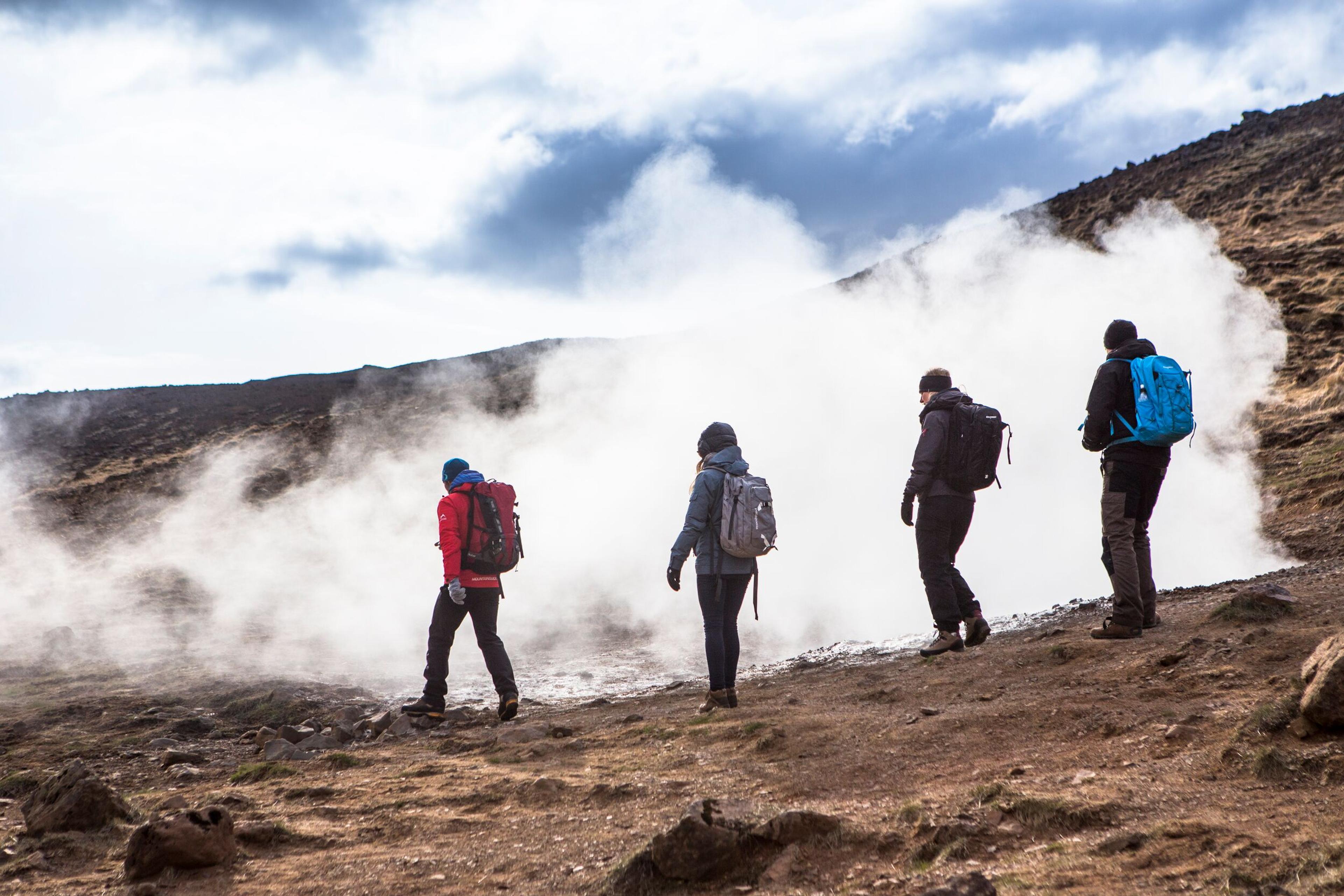 Group of hikers passing by a steam vent in Iceland.