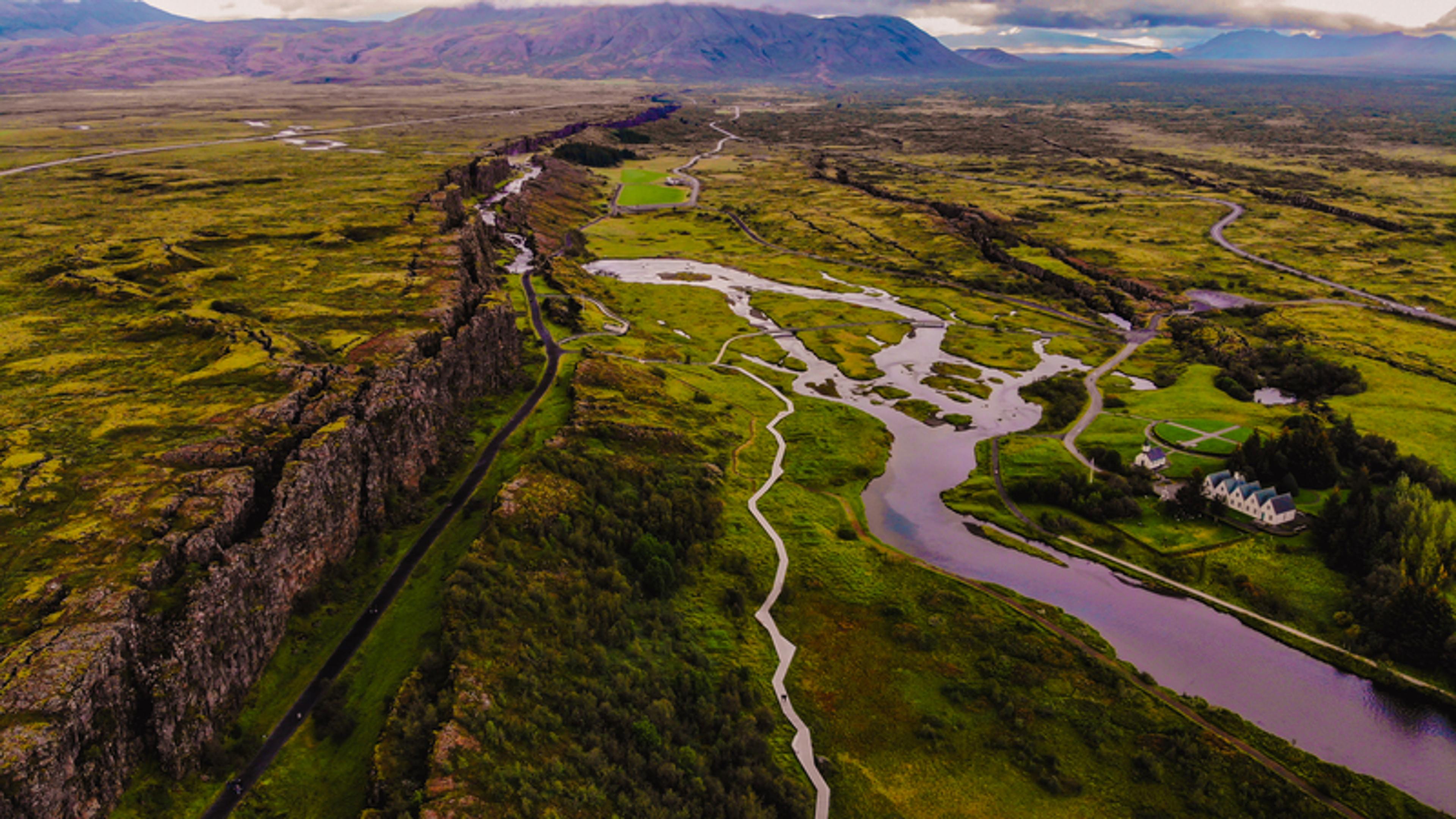 an aerial view of a river running through a lush green valley surrounded by mountains .