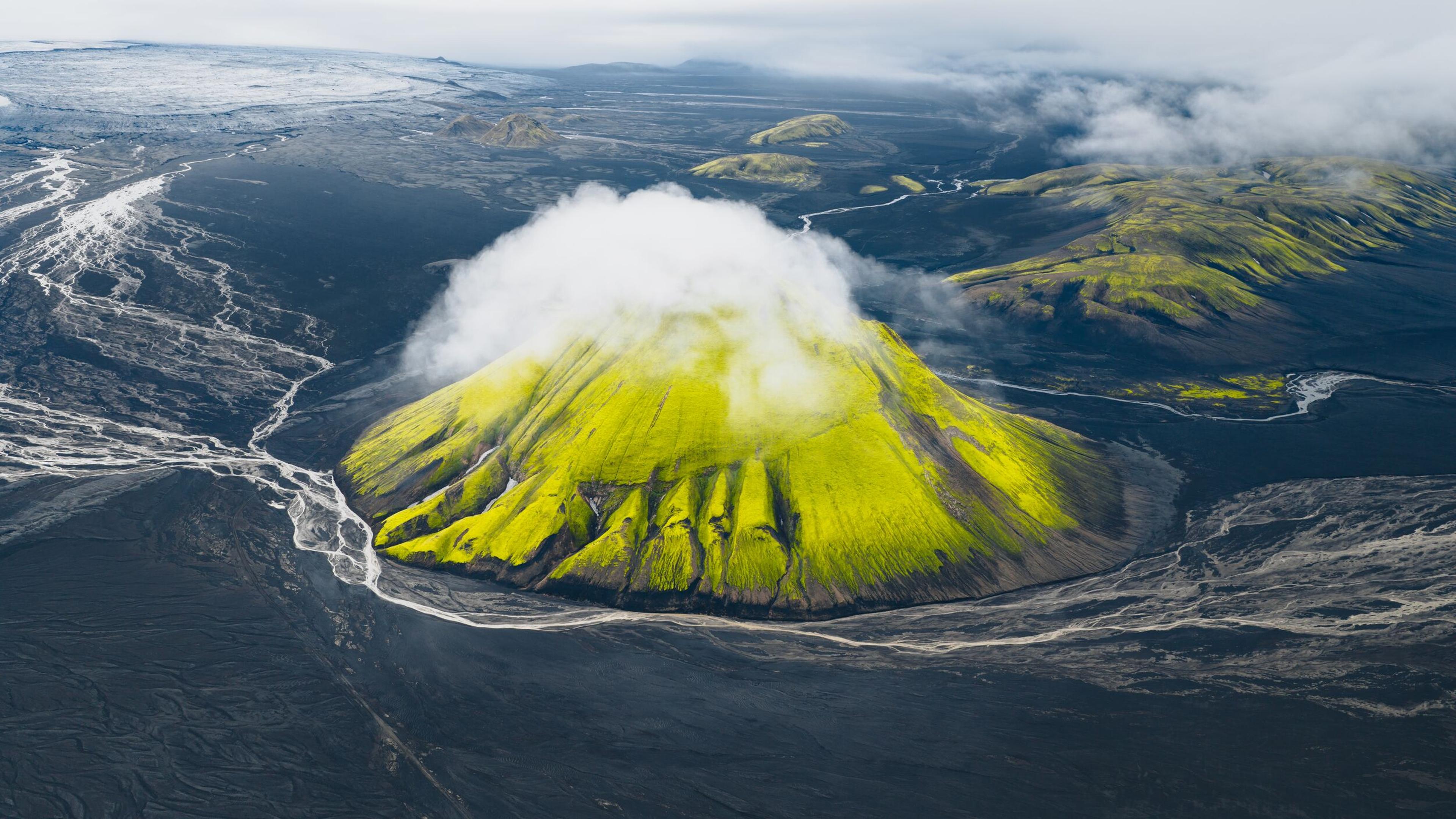 An overview of the landscape of the highland of Iceland with a green hill surrounded by black sands
