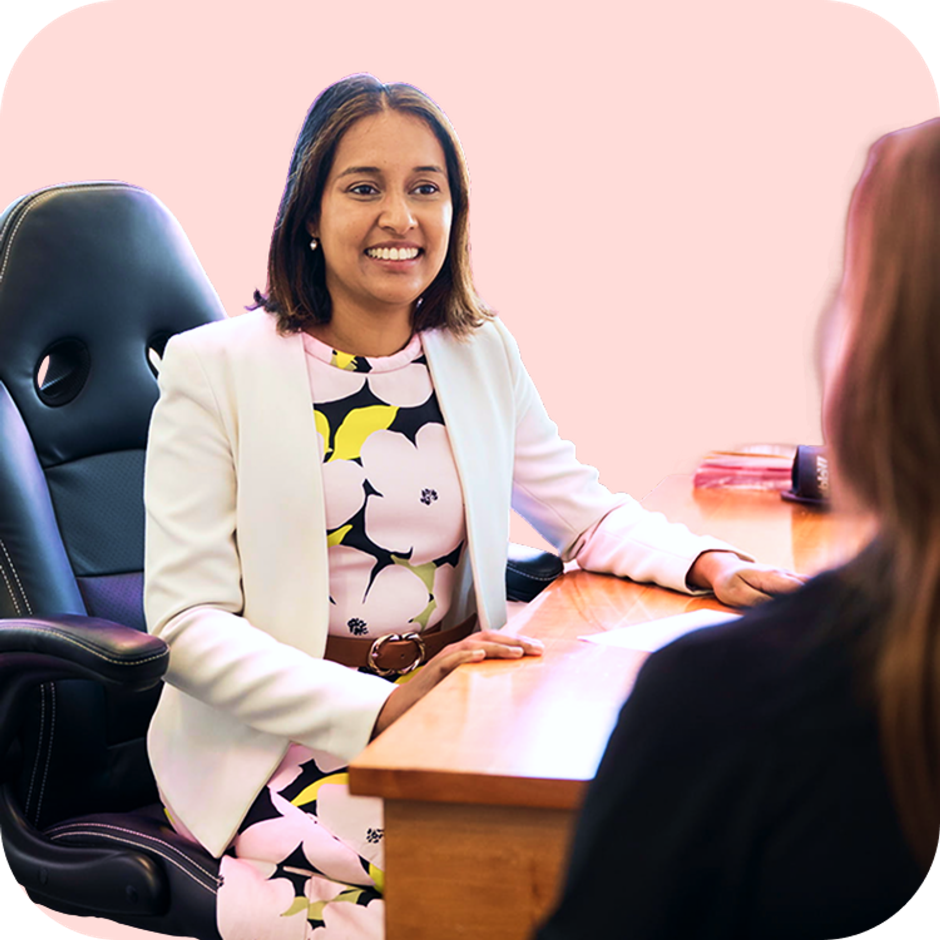 Dr Erica Remedios warmly smiles as she listens to a patient across her desk, creating a supportive and welcoming environment.