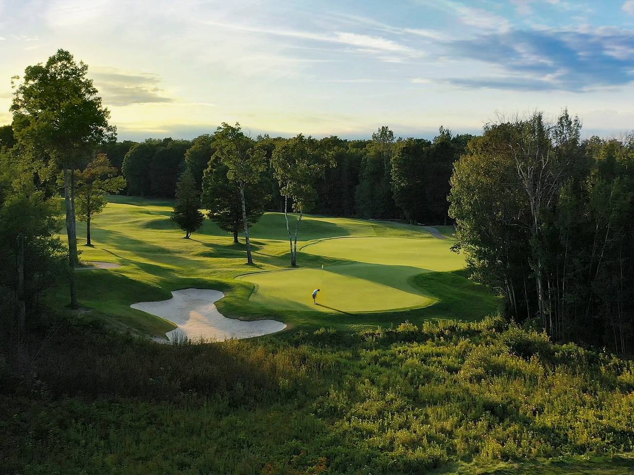 Golf course surrounded by trees at sunrise
