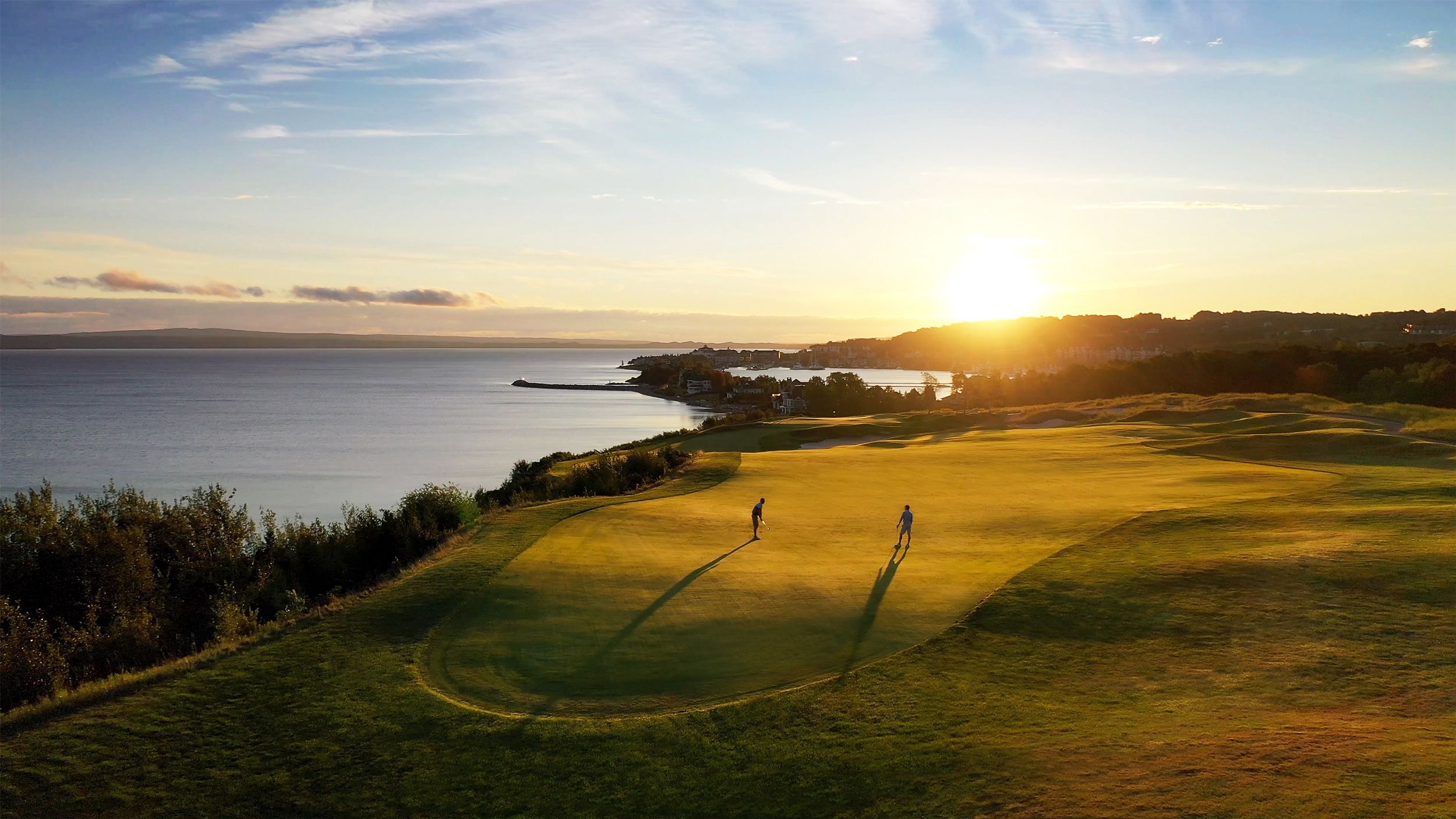 Golfers on lakefront course at sunrise