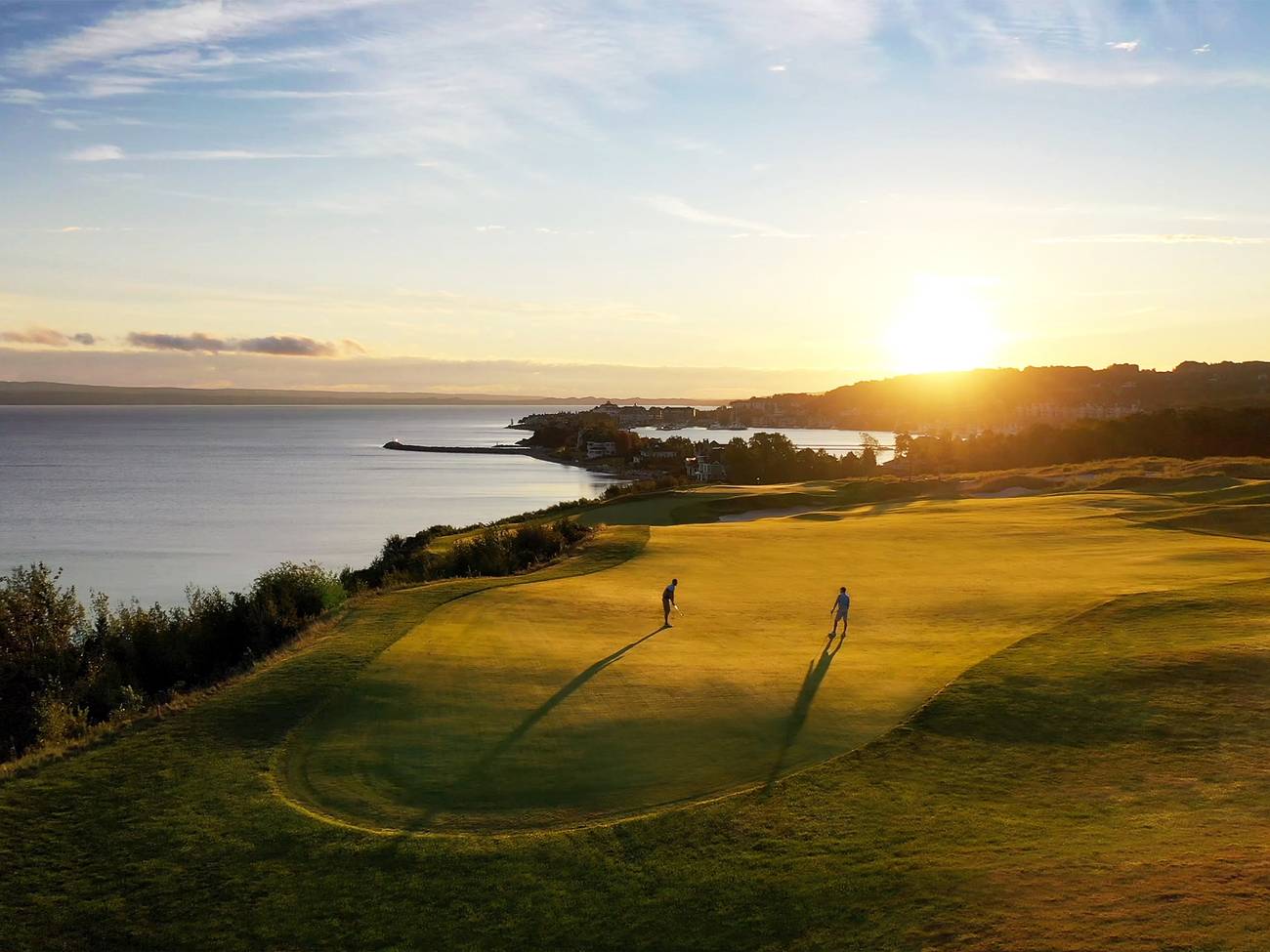 Golfers on lakefront course at sunrise