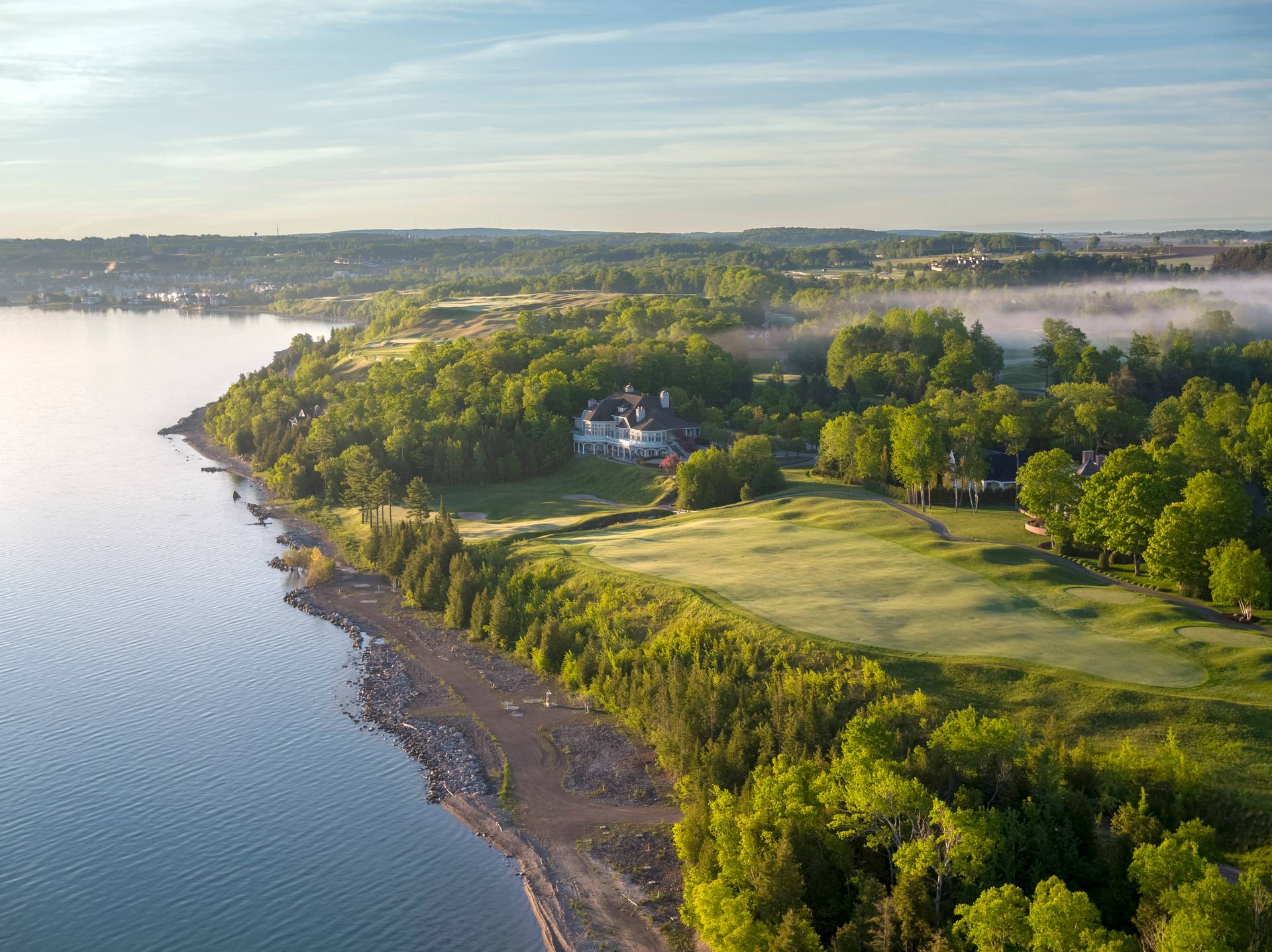 Bay Harbor Golf Club clubhouse and course along calm morning waters of Lake Michigan