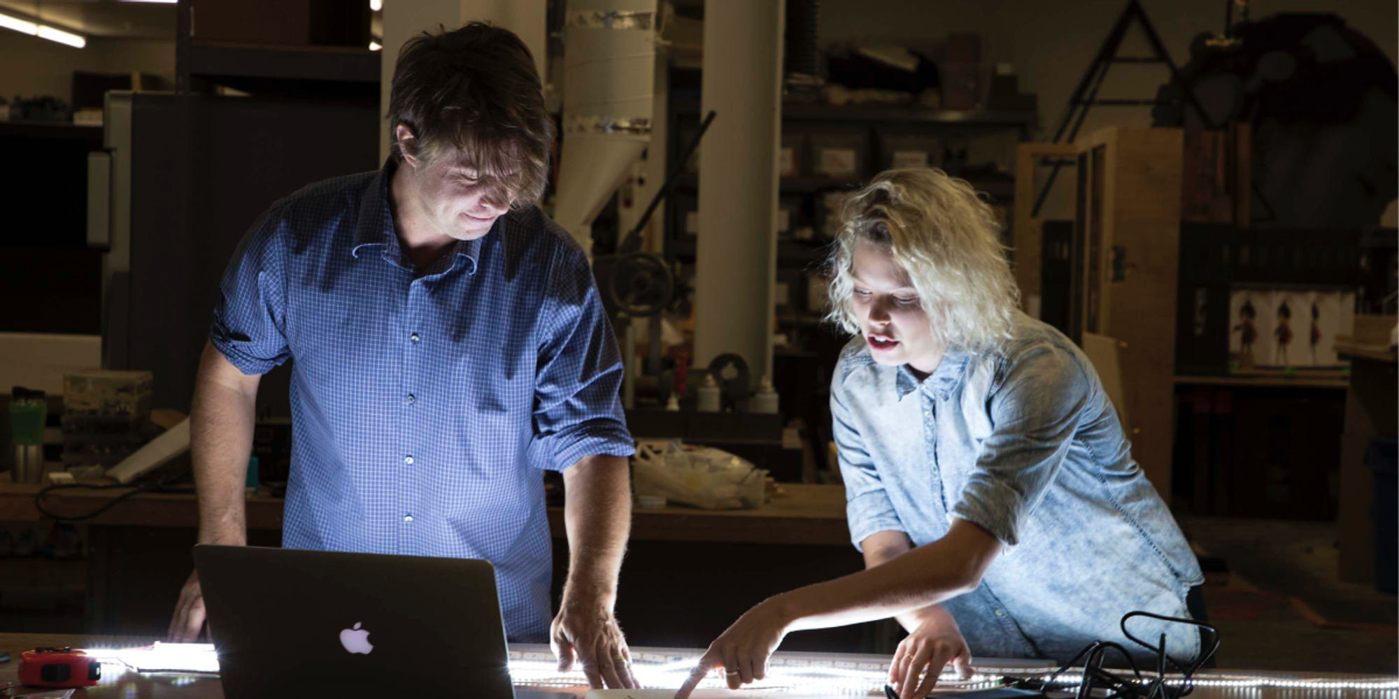 two coworkers working on a desk with a notebook