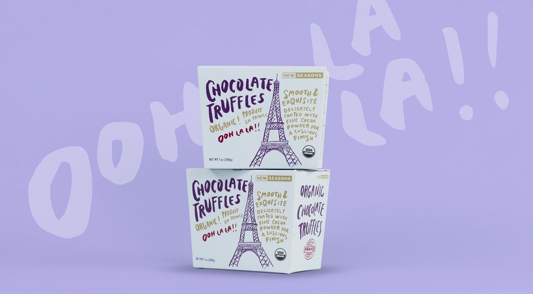 Two boxes of New Seasons chocolate truffles featuring an illustration of the Eiffel Tower, stacked on top of each other in front of a light purple background that reads “Ooh la la!”
