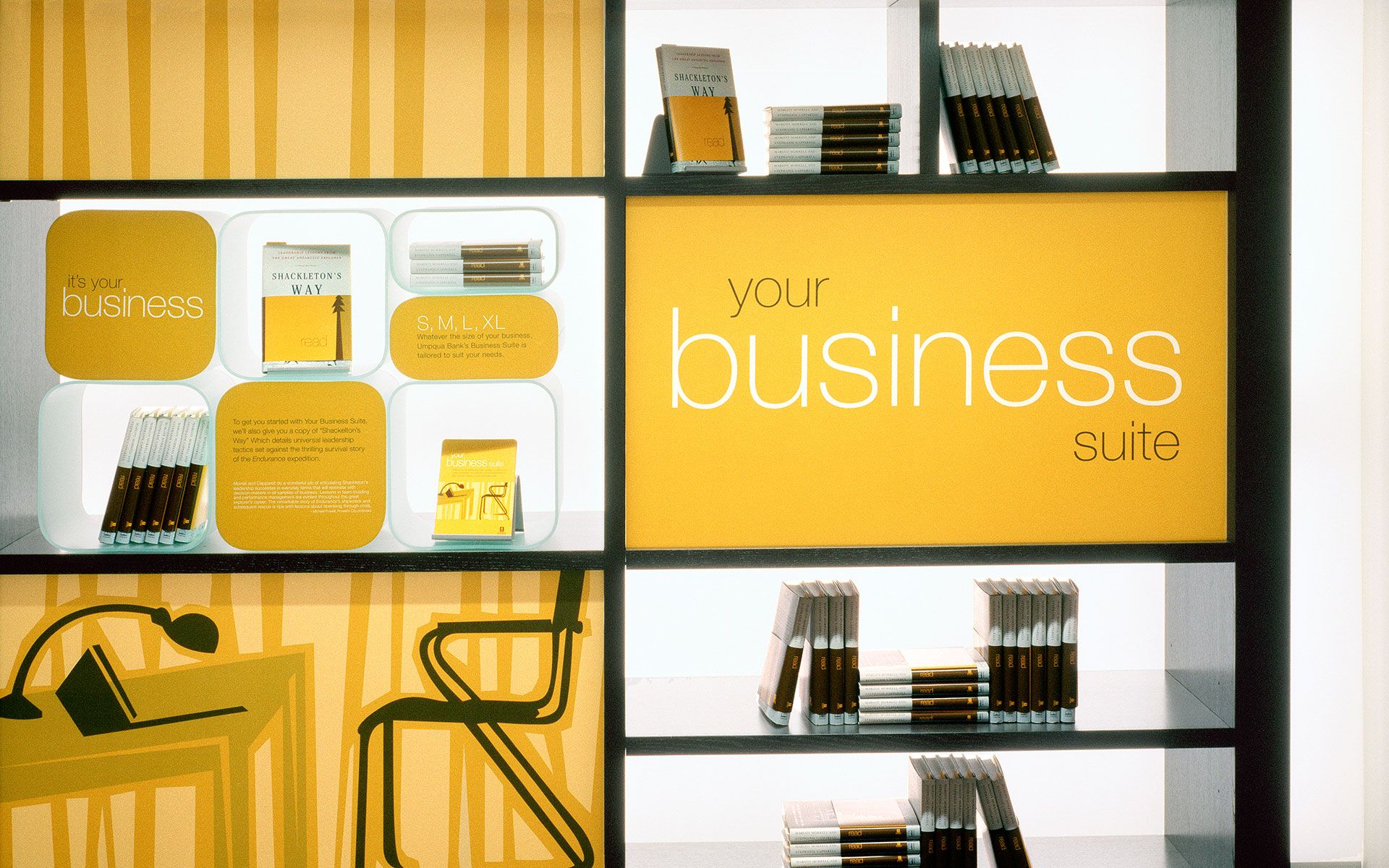 Bright orange backlit shelves with books and pamphlets, with the words “your business suite” printed on an orange panel