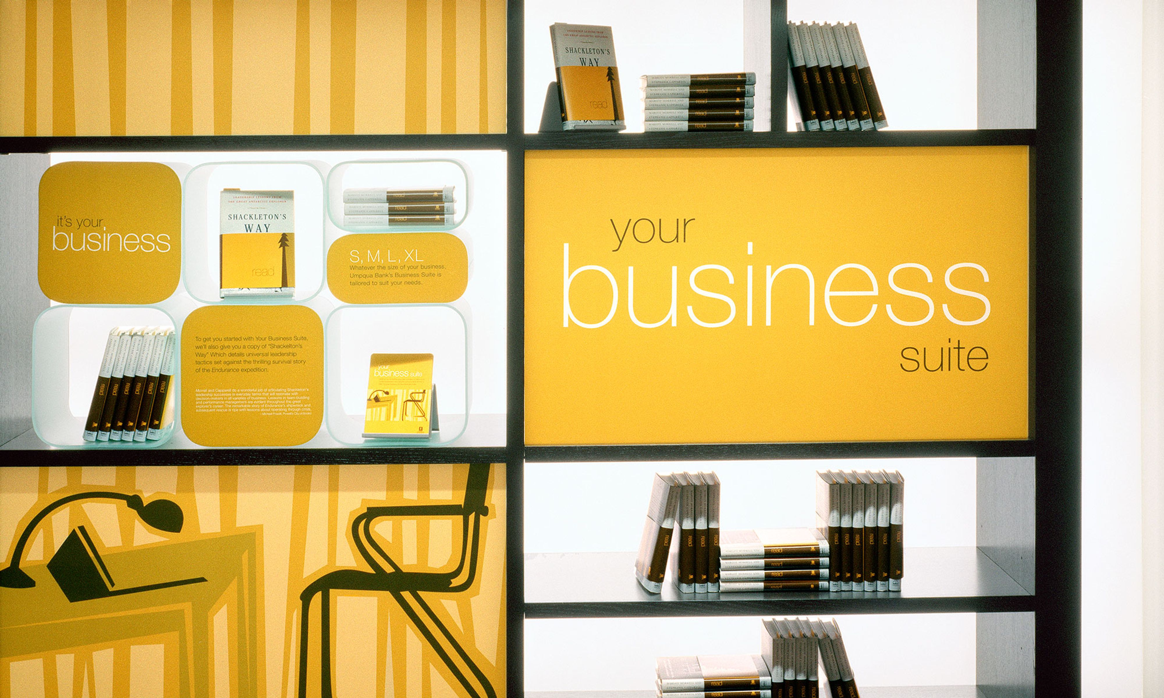 Bright orange backlit shelves with books and pamphlets, with the words “your business suite” printed on an orange panel