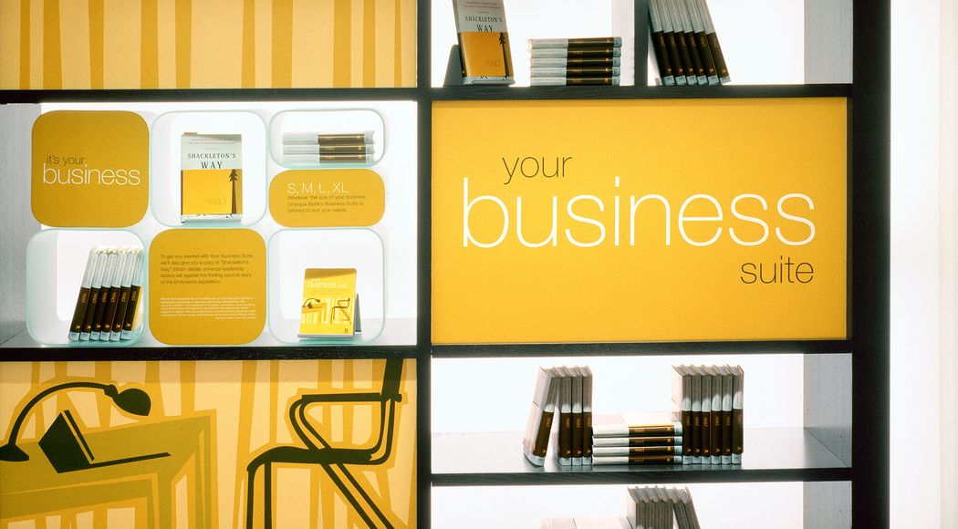 Bright orange backlit shelves with books and pamphlets, with the words “your business suite” printed on an orange panel