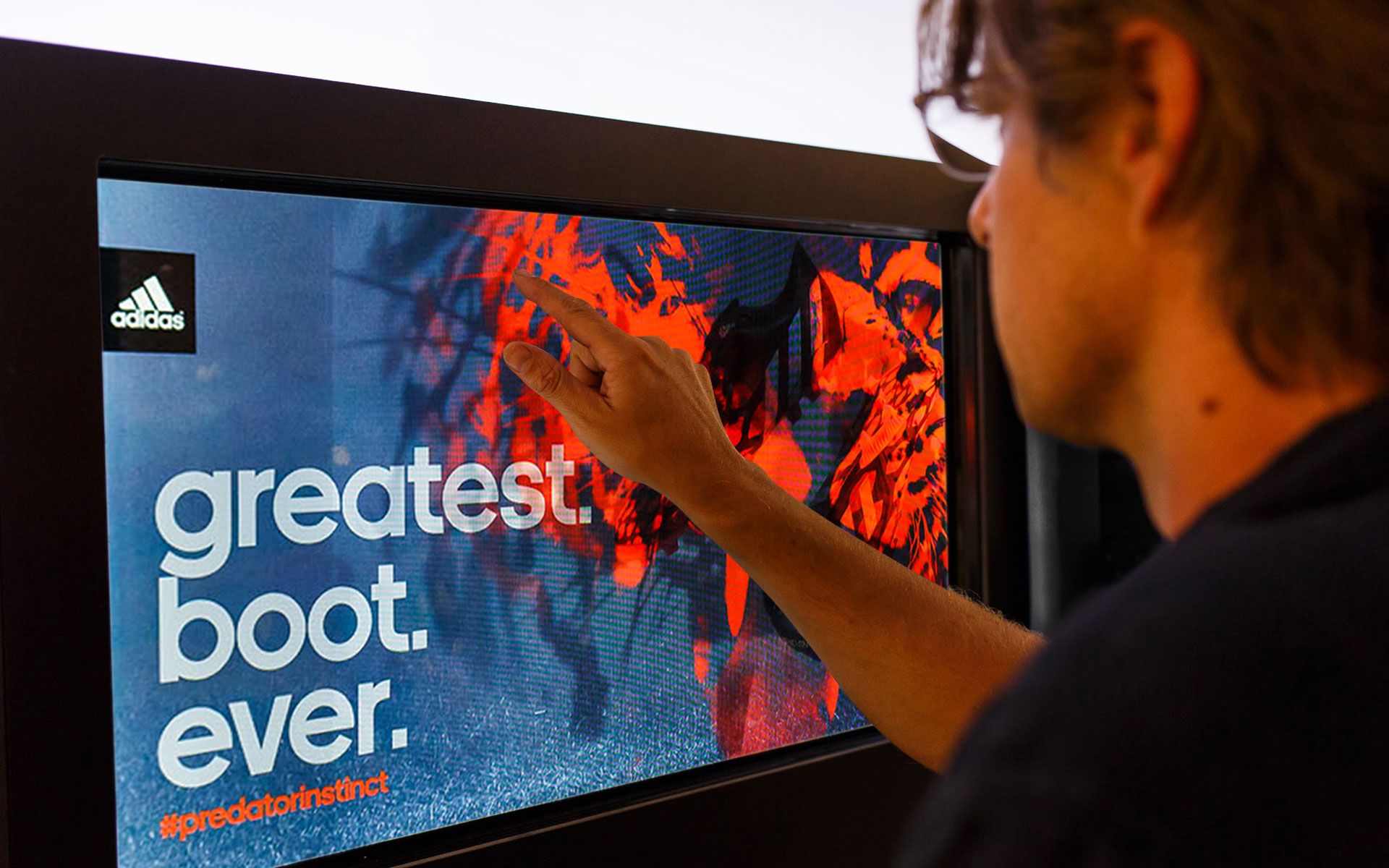 Person touching a touch screen that reads “Greatest. Boot. Ever.”
