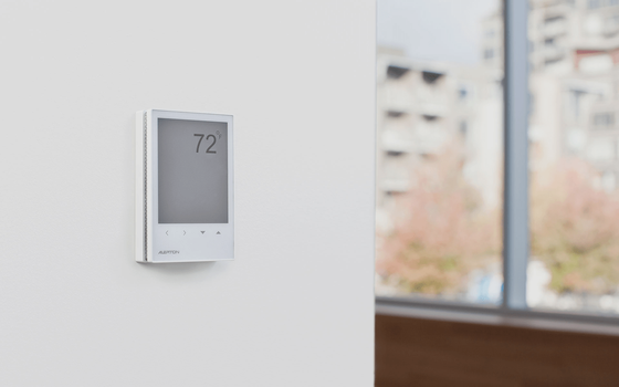 White rectangular digital thermostat on a plain white wall