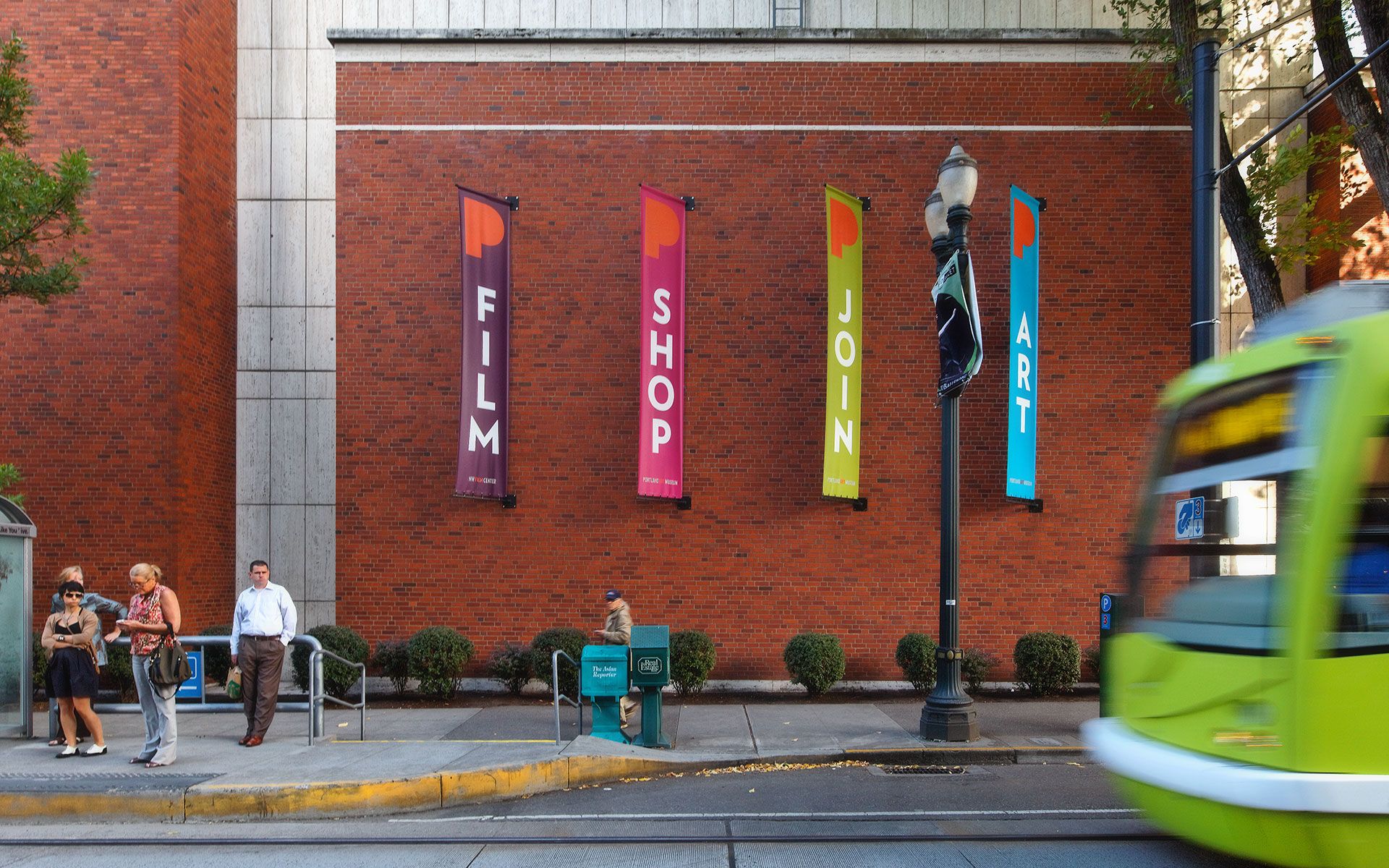 Four Portland Art Museum banners next to a bus stop that read “Film”, “Shop”, “Join”, and “Art”