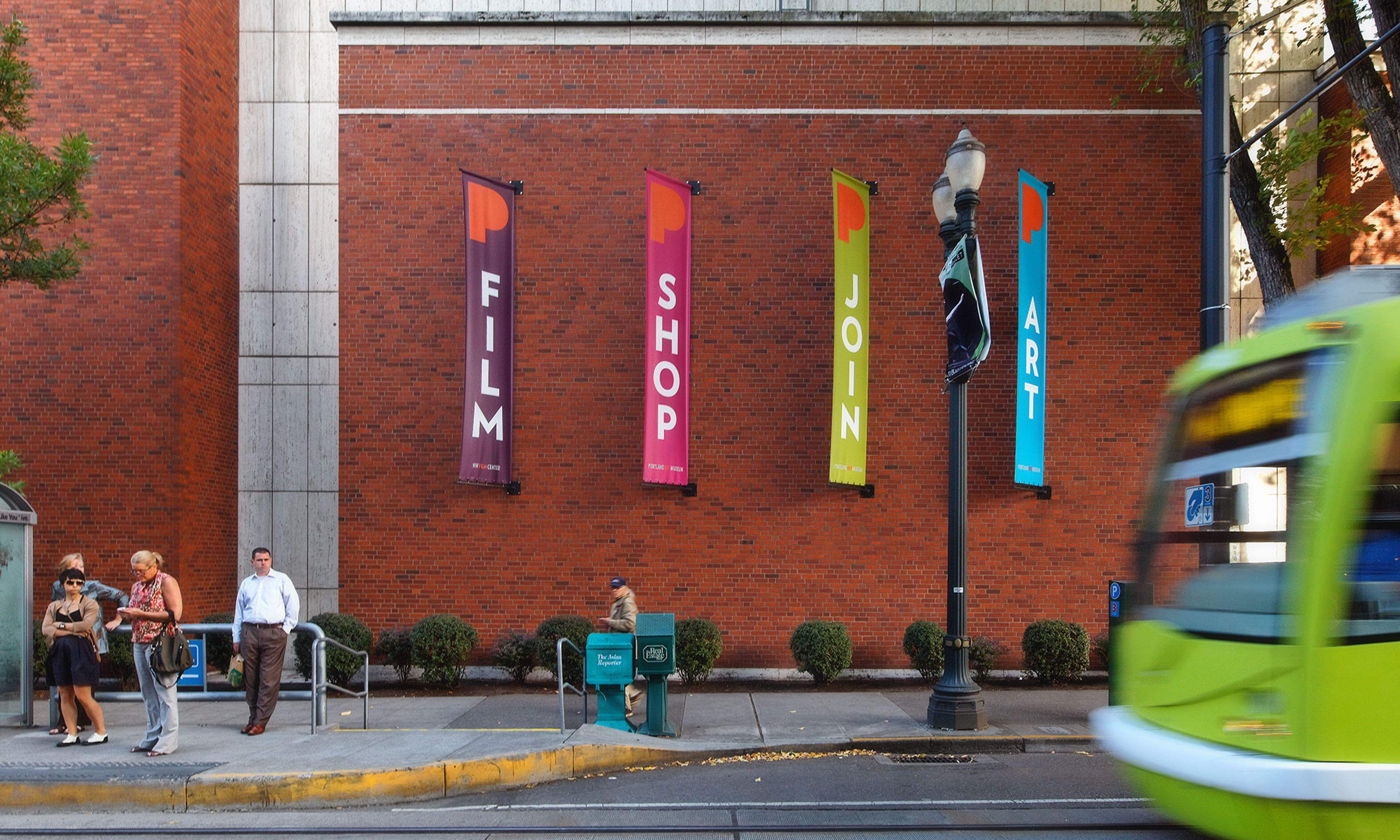 Four Portland Art Museum banners next to a bus stop that read “Film”, “Shop”, “Join”, and “Art”