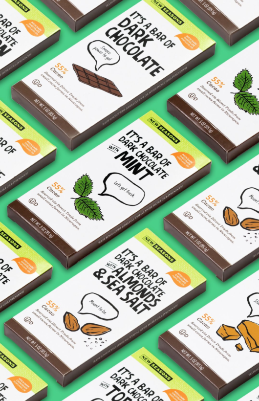 Several wrapped bars of chocolate made by New Seasons, including almond and sea salt, dark chocolate and mint, hazelnut, and toffee, placed at an angle on a green background