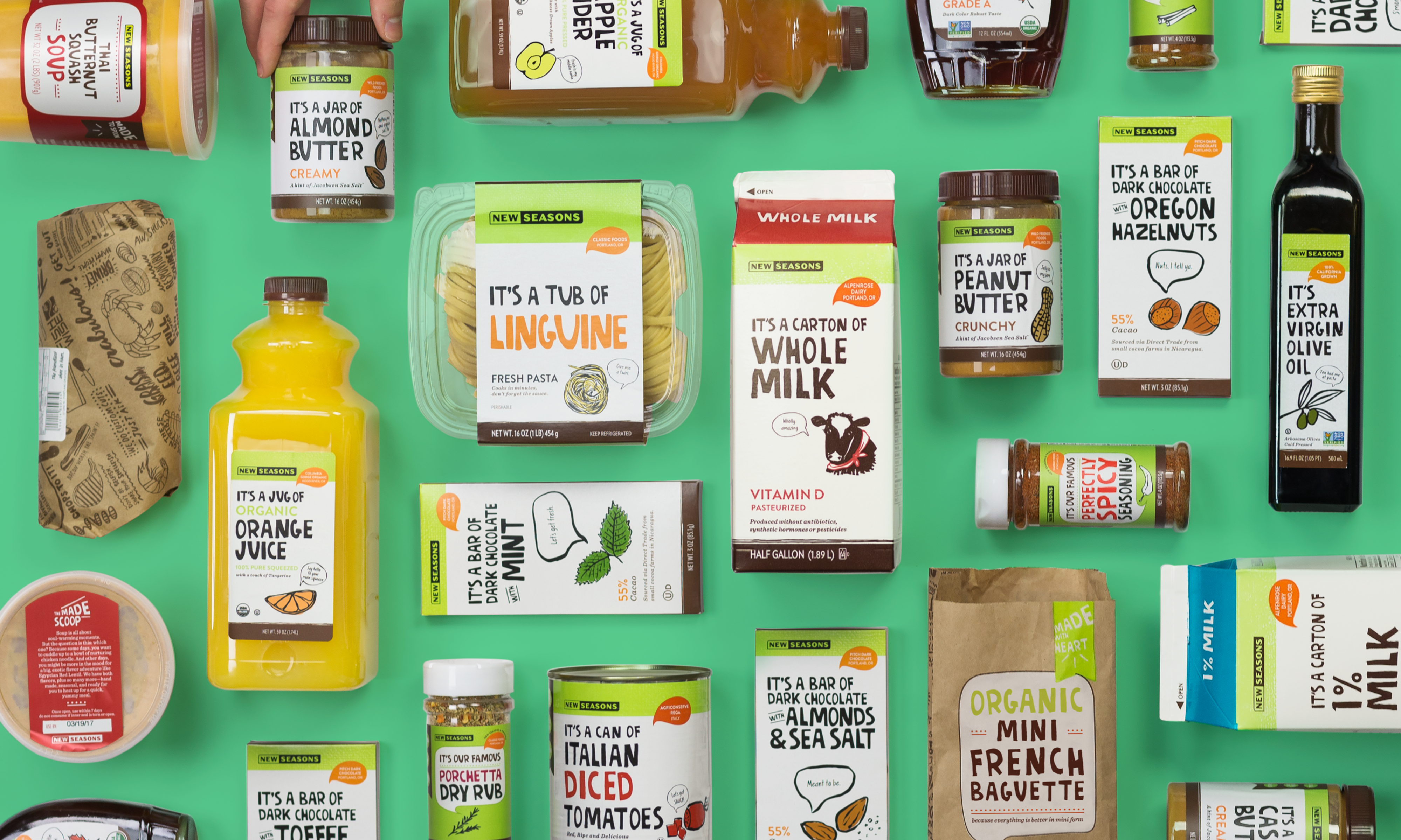 Several New Seasons products, including milk, orange juice, chocolate, spices, bread, and more placed neatly next to each other horizontally and vertically on a green background